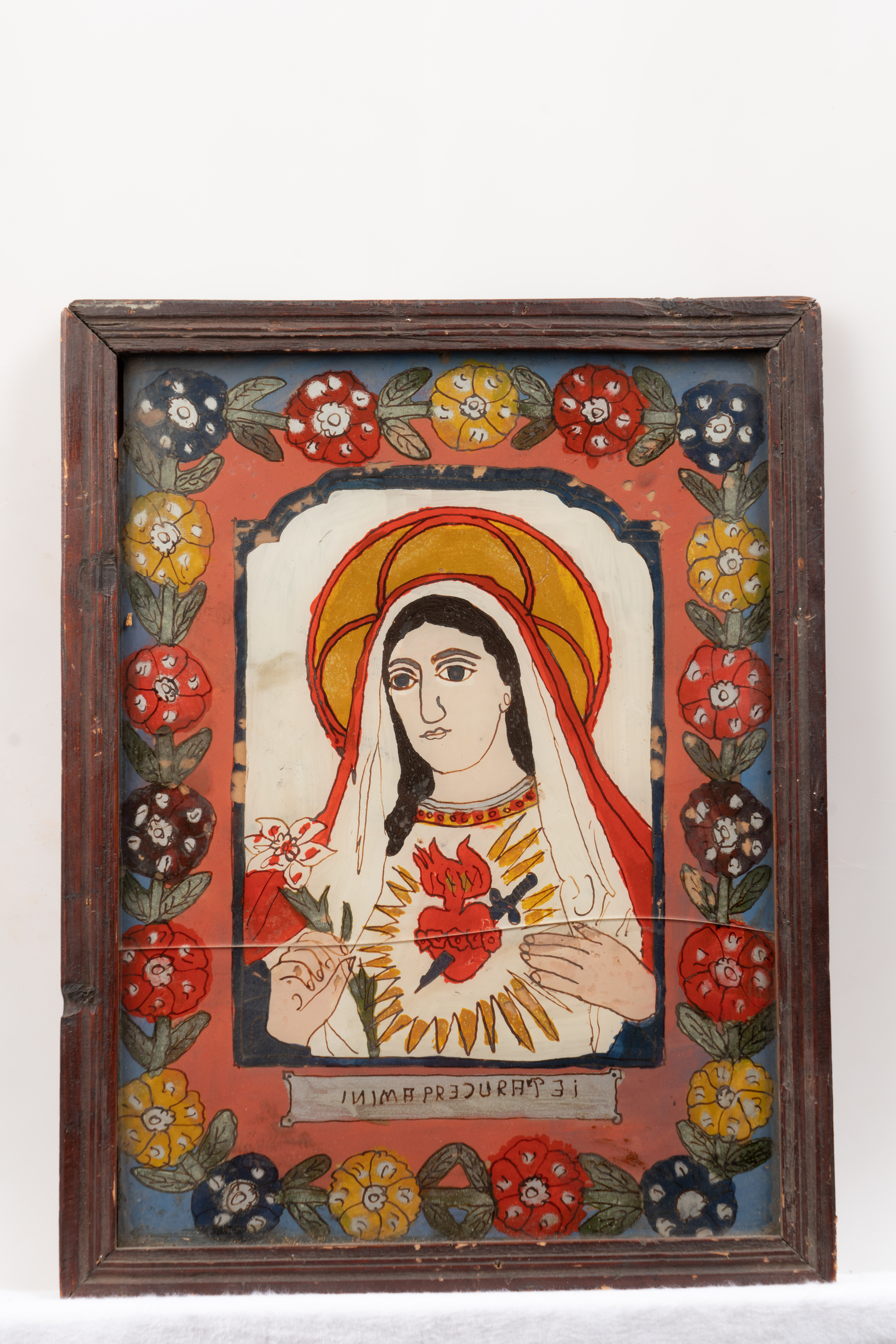 Redată bust, semiprofil, cu o inimă arzând și stăpunsă străpunsă de sabie, Fecioara Maria este încadrată de un chenar cu flori supradimensionate, multicolore. Stângăcia desenului și violența culorilor sunt atributele picturii de Mărgău.