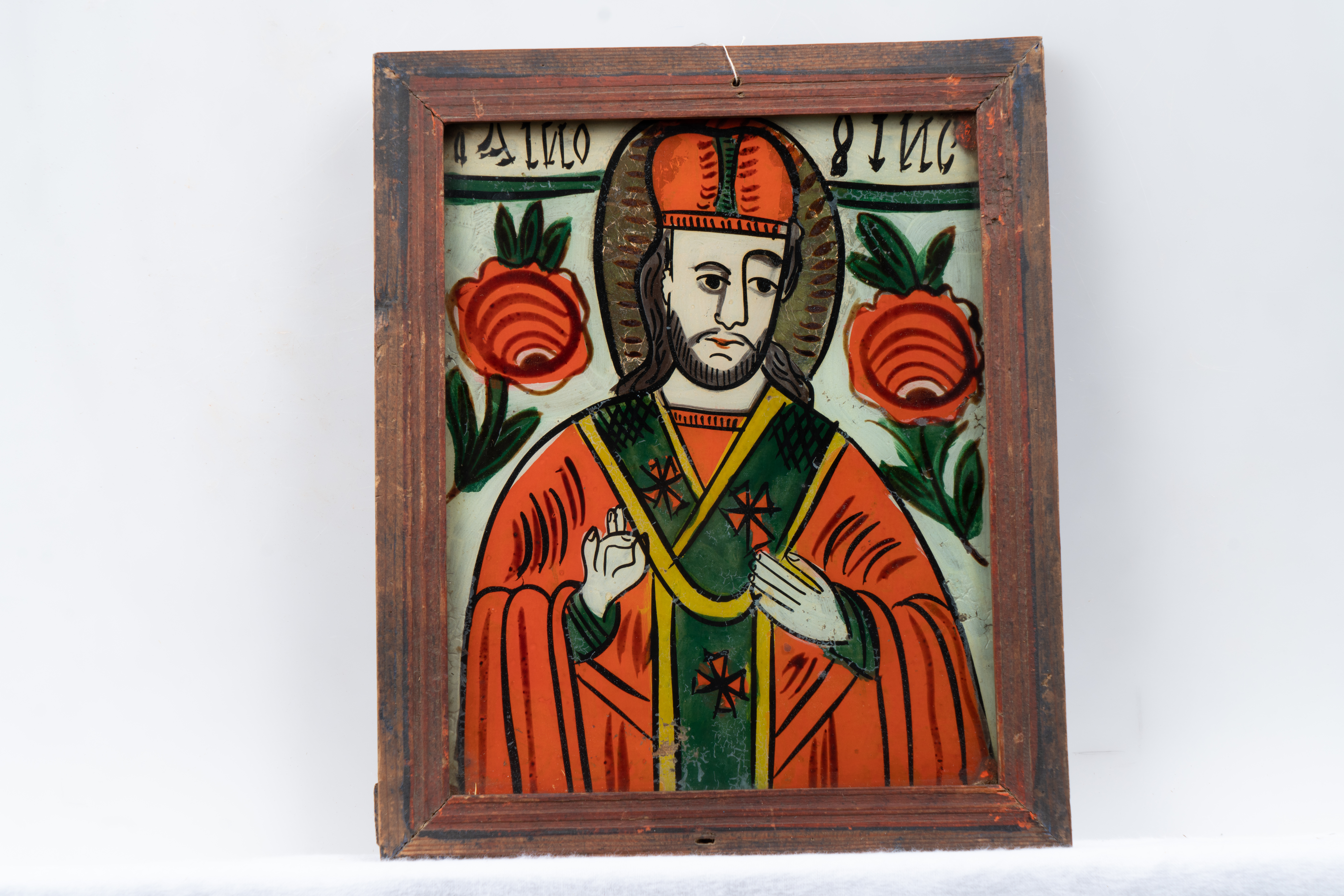 Pe un fundal albastru ceruleum, Sfântul Nicolae, redat semiprofil, bust, poartă omoforul verde, tivit cu galben, decorat cu cruci vermillion, desenate cu cerneală, peste felonul oranj. Carnația este albă, cu umbre schematice gri. Tradafiri roșii flanchează ierarhul.