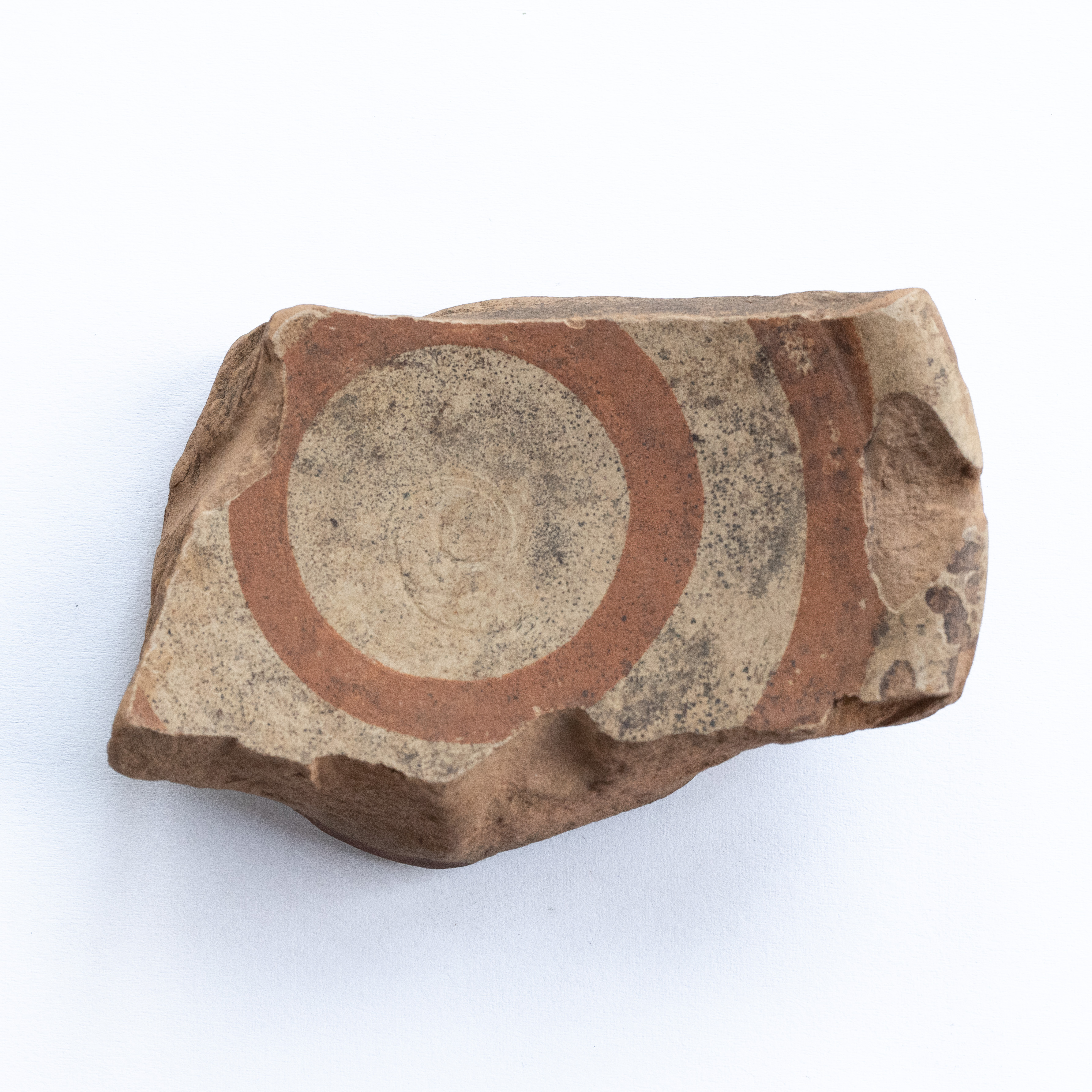 Fragment buton de capac, ornamentat cu cercuri concentrice realizate cu vopsea brun-roșcată pe angobă alb-gălbuie; prezintă urme de ardere secundară. Tehnica de realizare a fost inspirată de produsele elenistice (stilul Hadra). Motivul decorativ se înscrie în linia stilului figurativ specific ceramicii pictate din zona Sarmizegetusei Regia. Acest vas avea atât rol funcțional, cât și decorativ.
