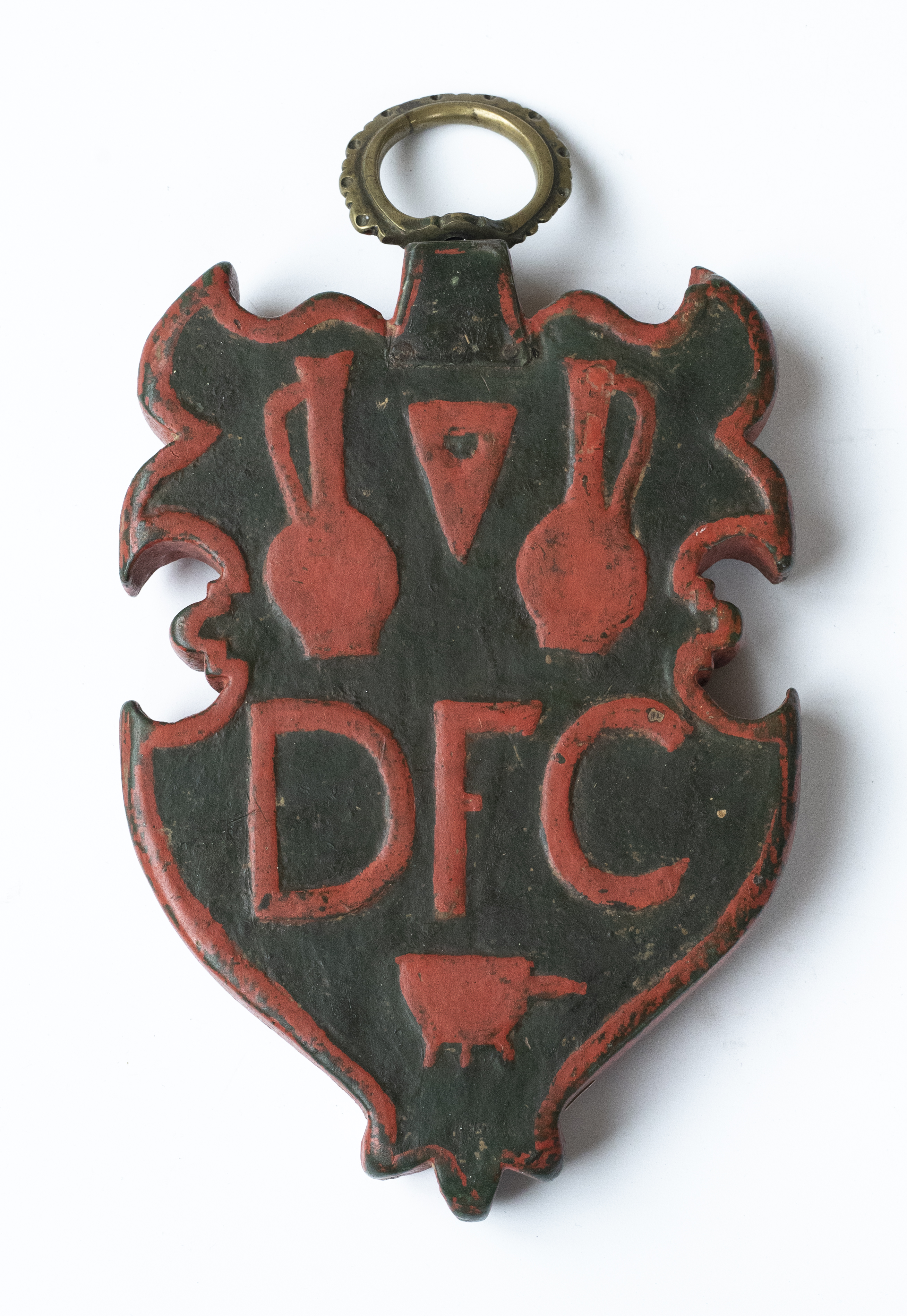 Tablă de breaslă de forma unui blazon heraldic, confecționată din lemn de esență tare. Marginea suportului, elementele de identificare și inscripțiile au fost evidențiate prin vopsirea într-un roșu puternic, în timp ce fundalul păstrează o nuanță de brun. Pe una dintre fețe sunt redate două vase de tip amforă în oglindă și jos o tigaie cu trei picioare, partea mediană a scutului fiind ocupată de inițialele care identifică breasla (Dési Fazékas Céh - Breasla olarilor din Dej). Pe fața opusă este montată o ușită de tablă metalică, rectangulară, încă funcțională, cu balamale din același material. În partea inferioară este redat un alt vas în stil antic, cu două torți de tip volută și anul 1715.