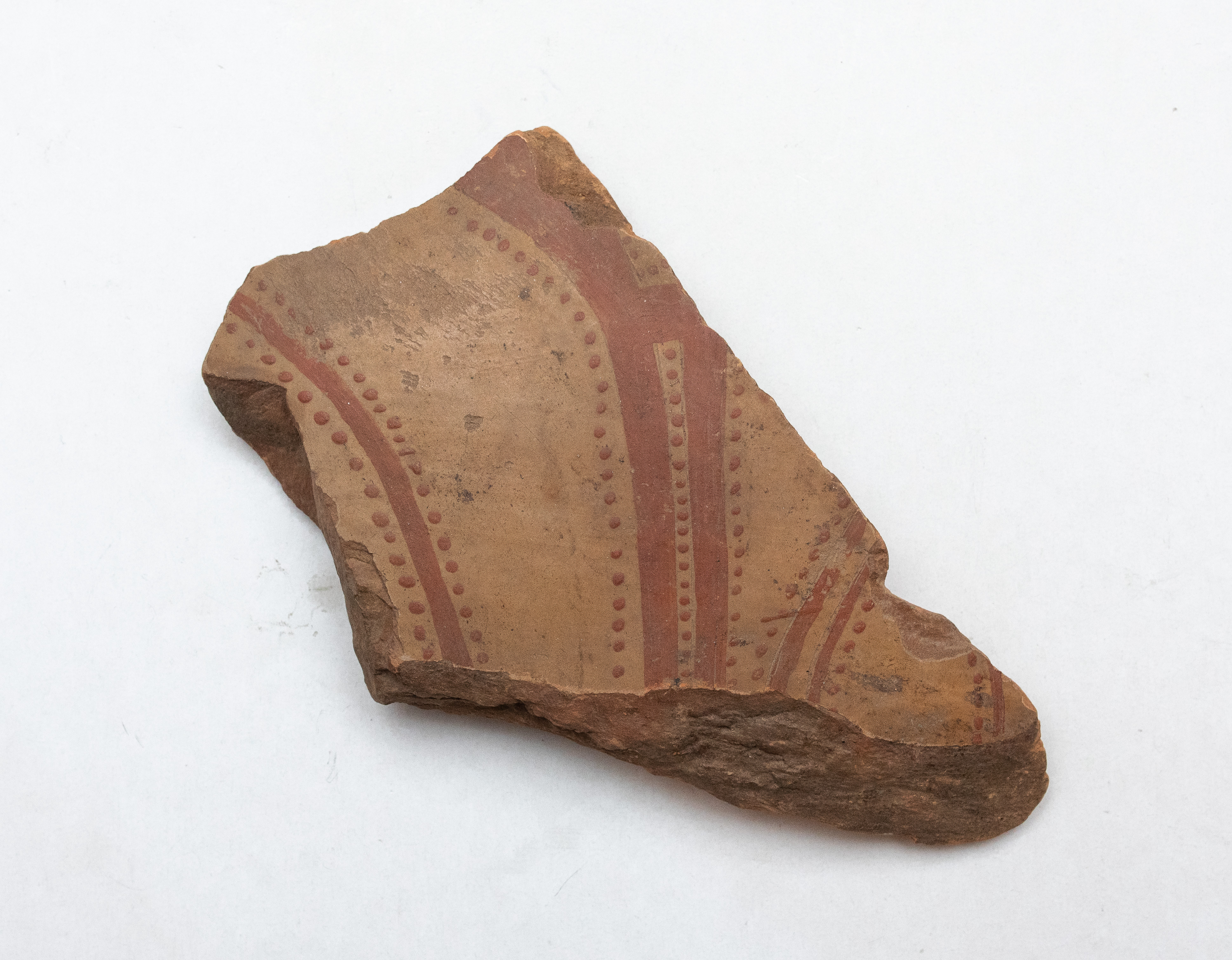 Fragment ceramic ce provine de la un vas ornamentat cu motive, probabil, vegetale realizate cu vopsea brun-roșiatică pe angoba alb-gălbuie. Tehnica de realizare a fost inspirată de produsele elenistice (stilul Hadra). Motivul decorativ se înscrie în linia stilului figurativ specific ceramicii pictate din zona Sarmizegetusei Regia. Acest vas avea atât rol funcțional, cât și decorativ.