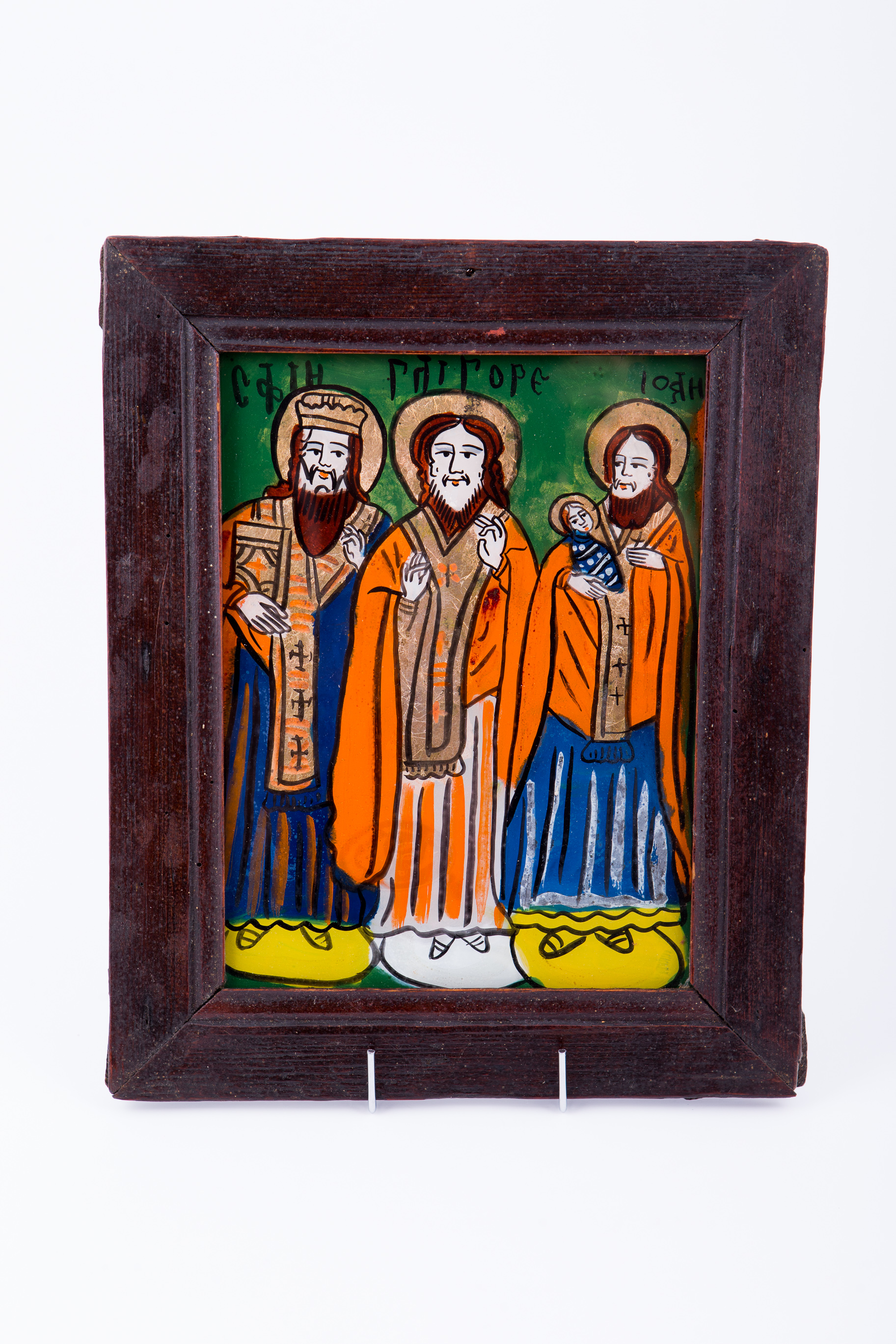 Cei Sfinți Trei Ierarhi Vasile cel Mare, Grigorie de Dumnezeu Cuvântătorul și Ioan Gură-de-Aur slujesc și săvârșesc Sfânta Liturghie împreună. Sunt înveșmântați în veșminte liturgice: sacos albastru, felon roșu vermillon, epitrahil auriu-bronziu. Sfântul Vasile cel Mare are Sfânta Evanghelie în mâna dreaptă. Sfântul Ierarh Grigorie de Dumnezeu Cuvântătorul Binecuvintează cu amândouă mâinile. Sfântul Ierarh Ioan Gură-de-Aur are în brațe un prunc înfășat. Cei trei Sfinți Ierarhi stau cu picioarele pe perinițe rotunde de culori alternative: galben-ocru și alb. Cromatica este luminoasă și armonioasă. Este o icoană specifică picturii de Țara Oltului, din centrul Șcheii Brașovului.