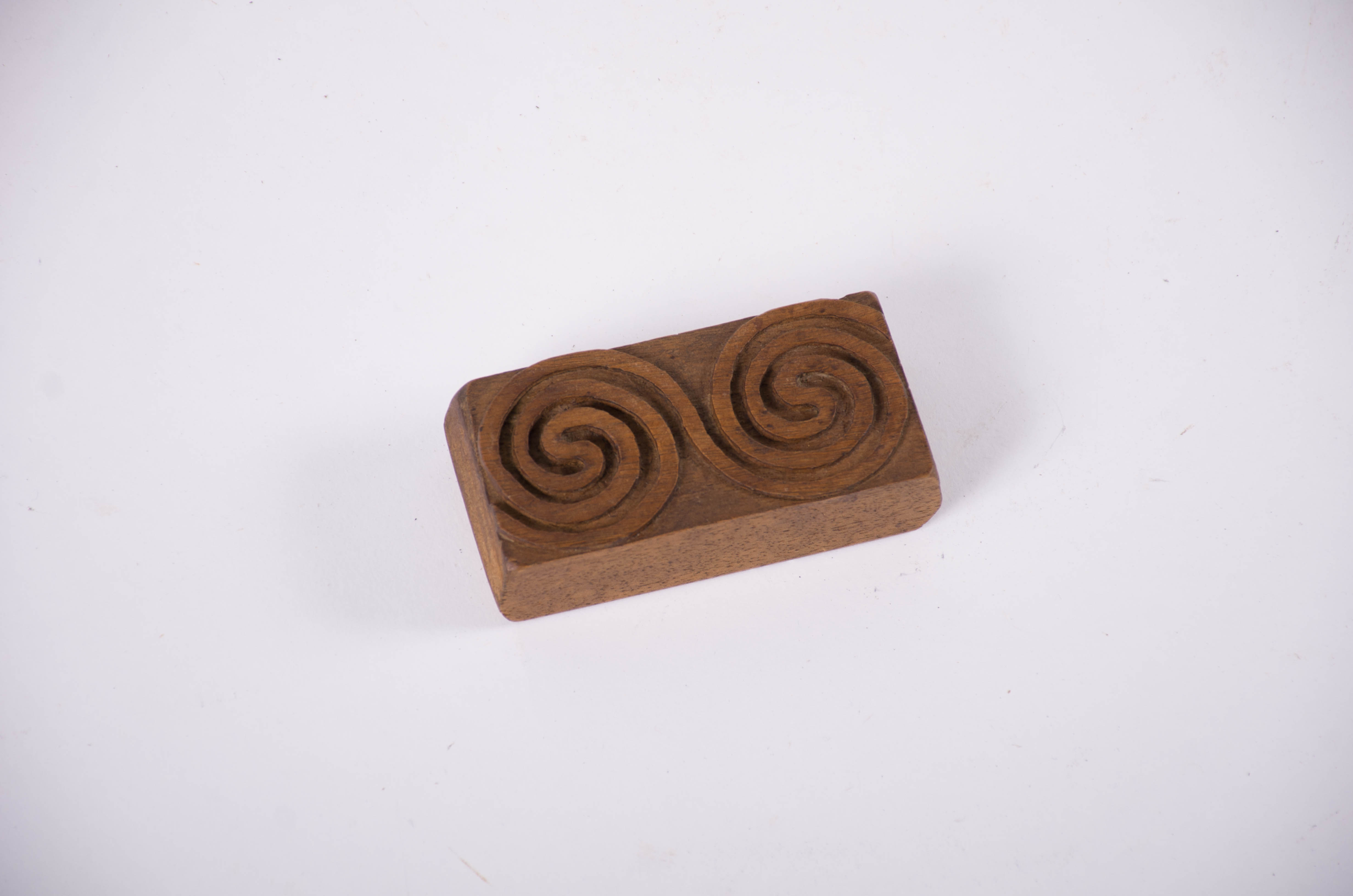 Tipar de formă dreptunghiulară având sculptate două spirale duble legate între ele într-o formă de opt. Cromatică: culoarea patinată a lemnului.