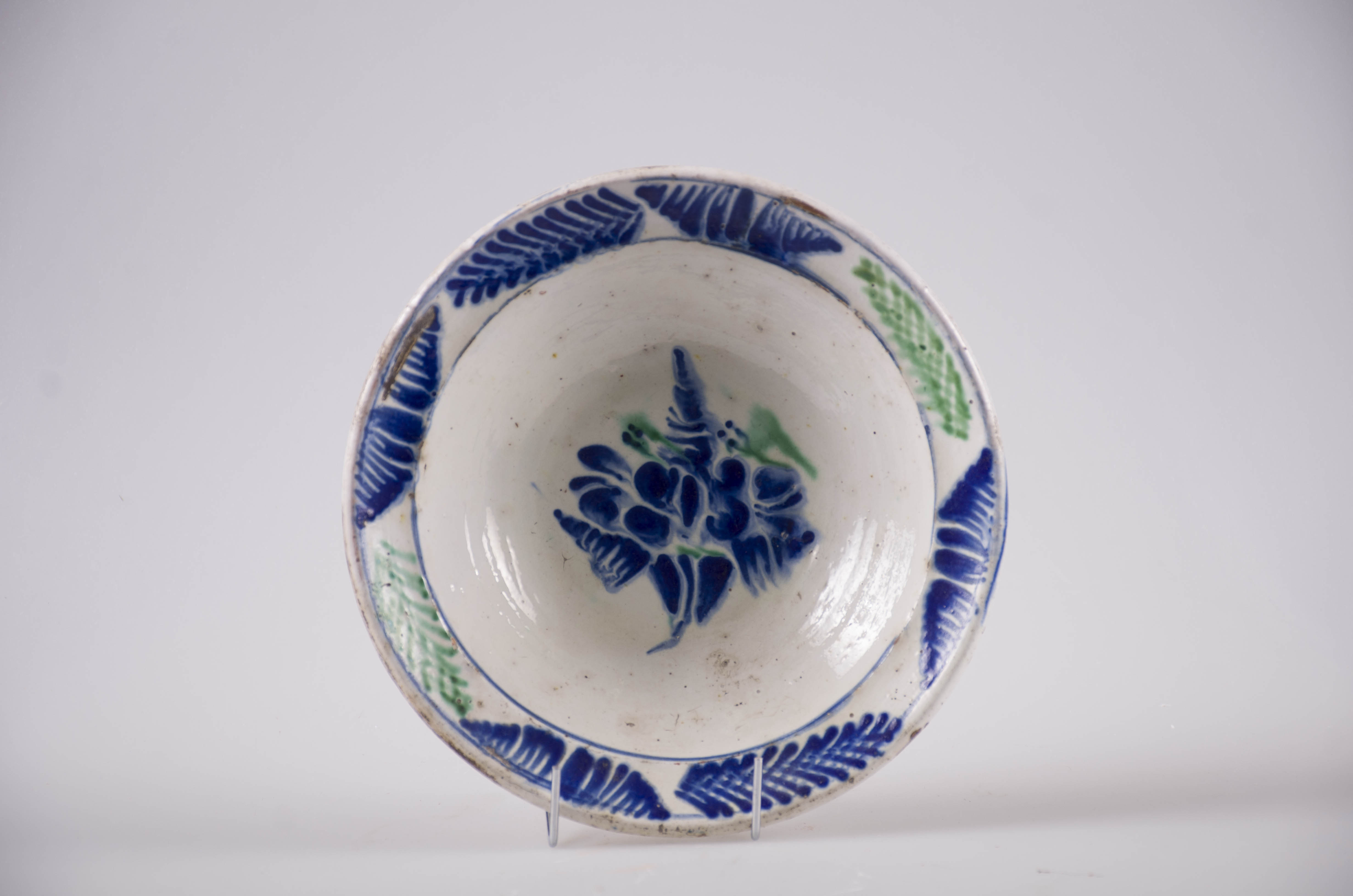 Blid de formă tronconică cu buza evazată, Smălțuit la interior. Decorul este format din ornamente florale dispuse pe motiv central: floare; motive marginale, fitomorfe: brăduț. Cromatică: verde și albastru pe fond alb.