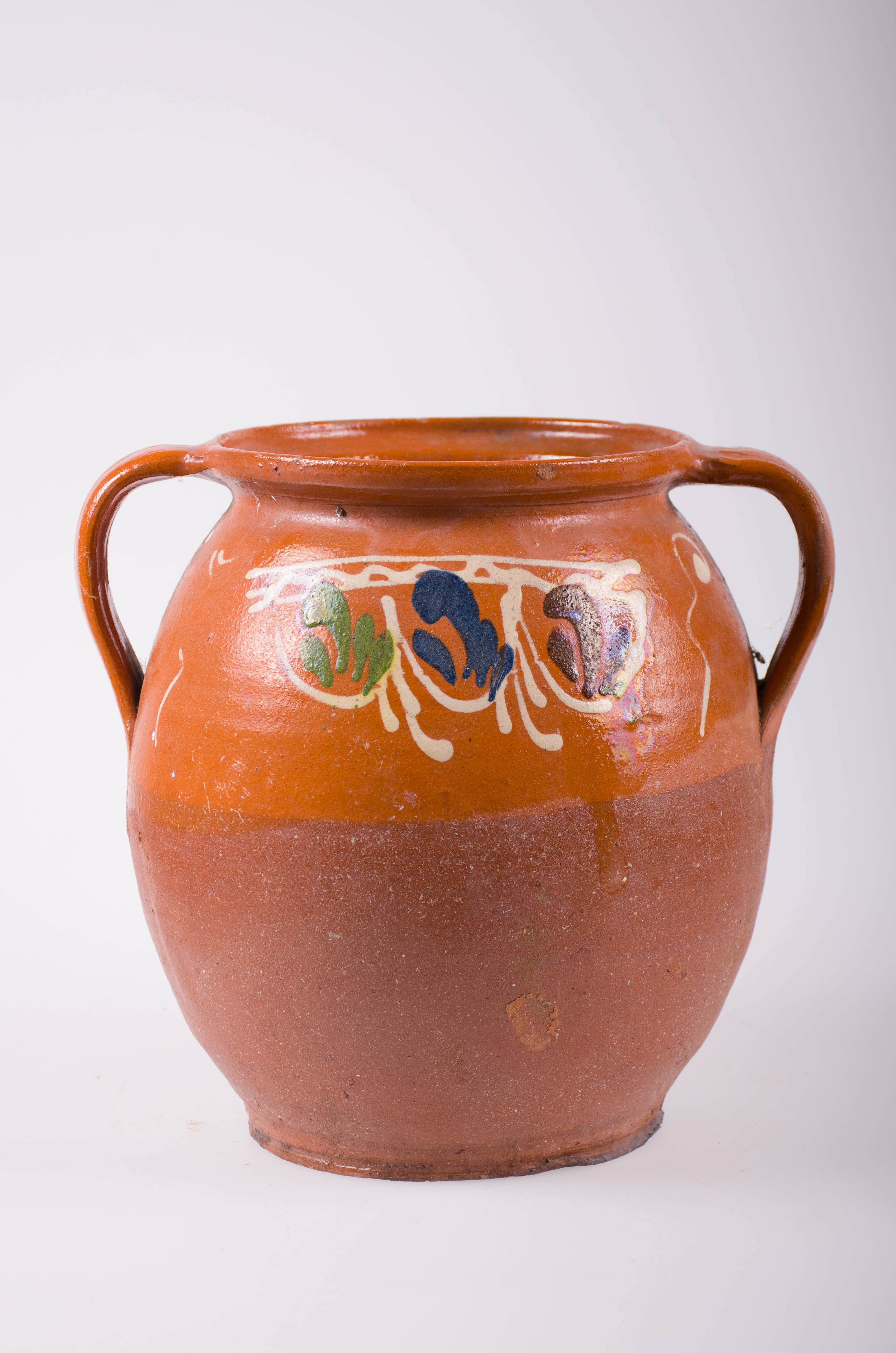 Oala de ceramică de formă bitronconică; înspre jumătatea inferioară a vasului nesmăltuită, dar smălțuită în partea superioară și în interior: Două toarte dispuse simetric de o parte și de alta a vasului. Decorată cu motive florale și vegetale stilizate cât și geometrice: linii ondulate. Cromatică: fond maro; motive: albe; maro; albastru; verde.