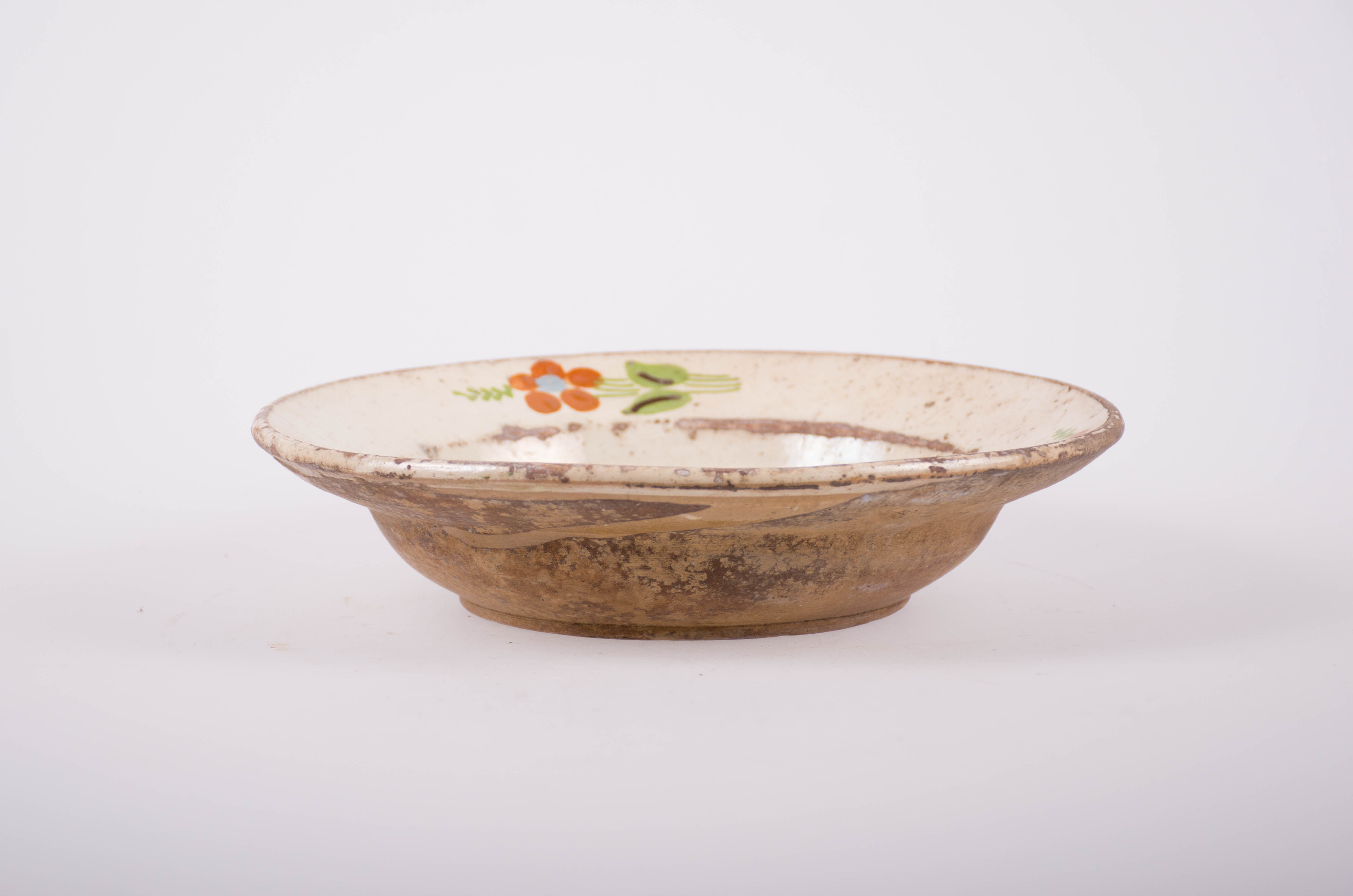 Blid tronconic din ceramică, smălțuit în interior, decorat cu motive florale și fitomorfe stilizate; la fel și pe buza blidului. Cromatică: fond alb-gălbui; motive: maro; verde; albastru.