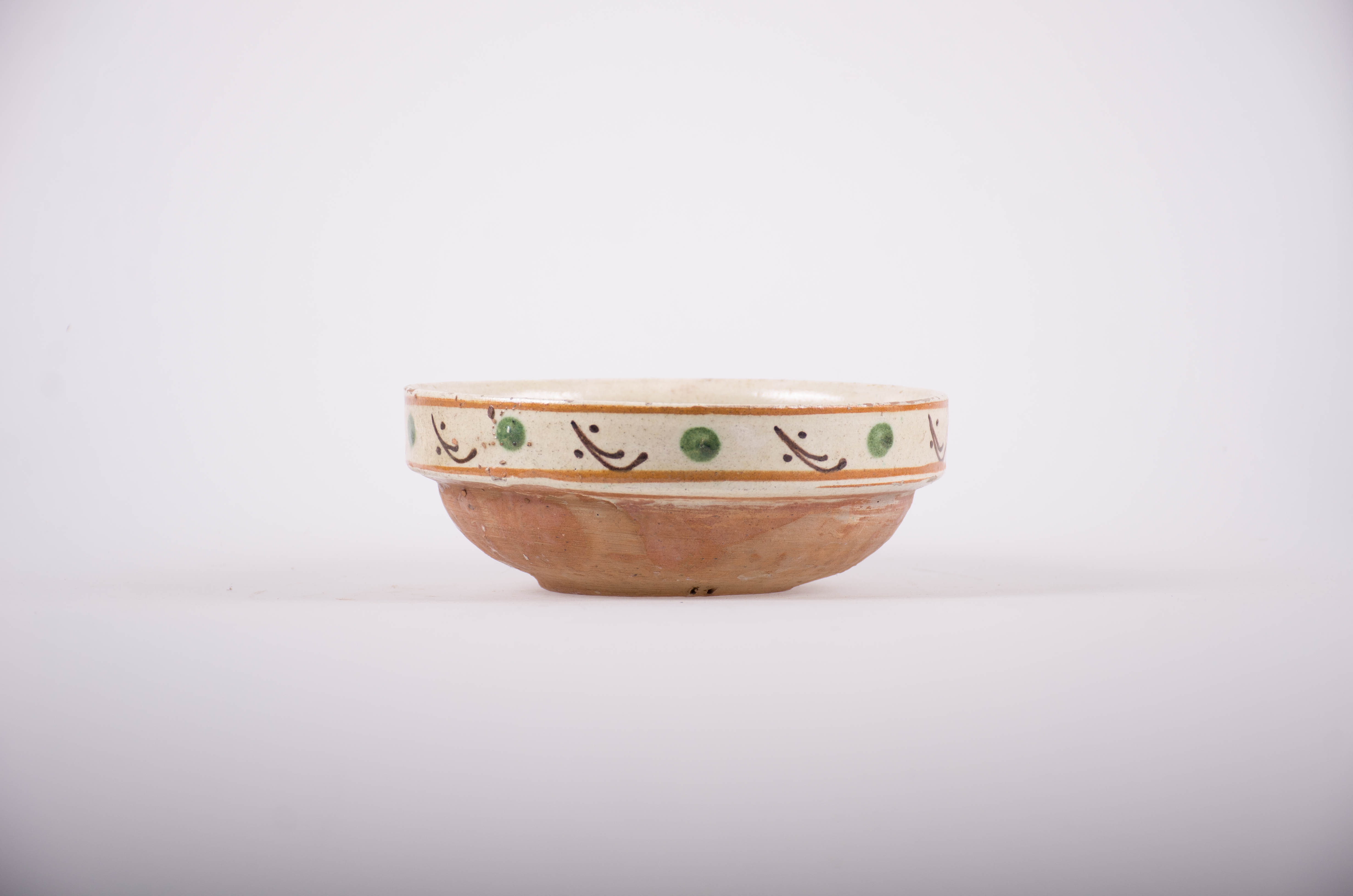 Blid din ceramică, de fomă tronconică, smălțuit în interior; decorat cu motive florale si geometrice. Cromatică: fond alb-gălbui; motive: maro; alb; albastru; verde; la buza și la interior e smălțuit; pe fond alb-galbui, este decorat cu linii și puncte maro și verzi.