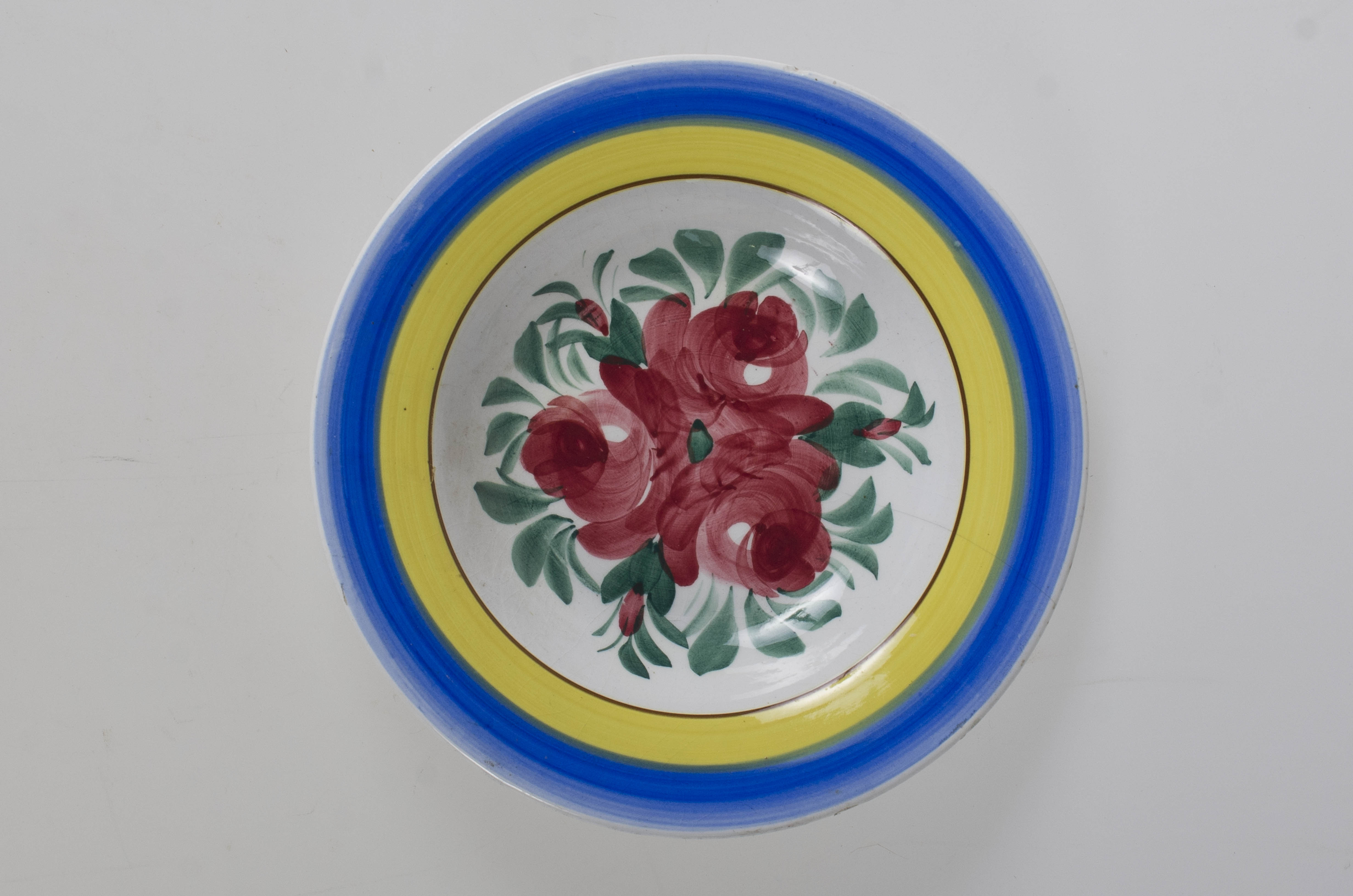 Farfurie de formă tronconică, adâncită; motive florale în centru (trandafiri); pe margine este decorat cu trei cercuri concentrice. Pe fund este o ștanță: o casă cu o pasăre pe acoperiș cu inscripție deasupra: ”MAGYAR” și dedesubt: ”1971” și un cuvânt indescifrabil. Pe fundul vasului sunt două incizii în care este introdus un șnur folosit la agățarea vasului pe perete. Vasul este smălțuit interior-exterior. Decor obținut prin pictare. Cromatică: fond: alb, motive: roșu; verde; albastru; galben.