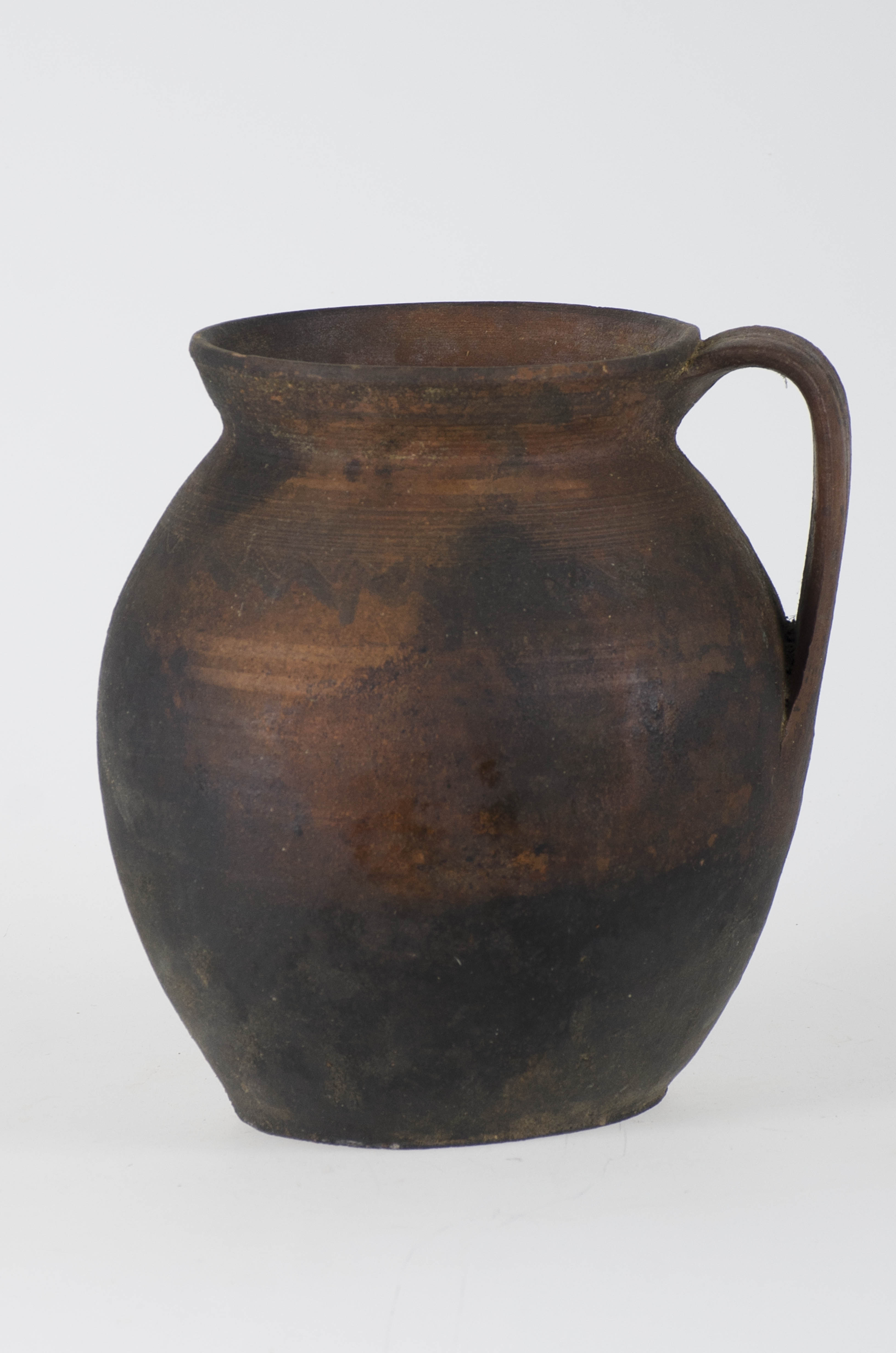 Vas ceramic de dimensiuni medii, bitronconic, prevăzut cu o toartă. Vasul a fost realizat la roata olarului, decorat, uscat, iar mai apoi ars. Posibilul decor pictat a fost acoperit de stratul de funingine, cauzat de folosirea la foc deschis. Culoarea vasului este maro și negru de la stratul de uzură.