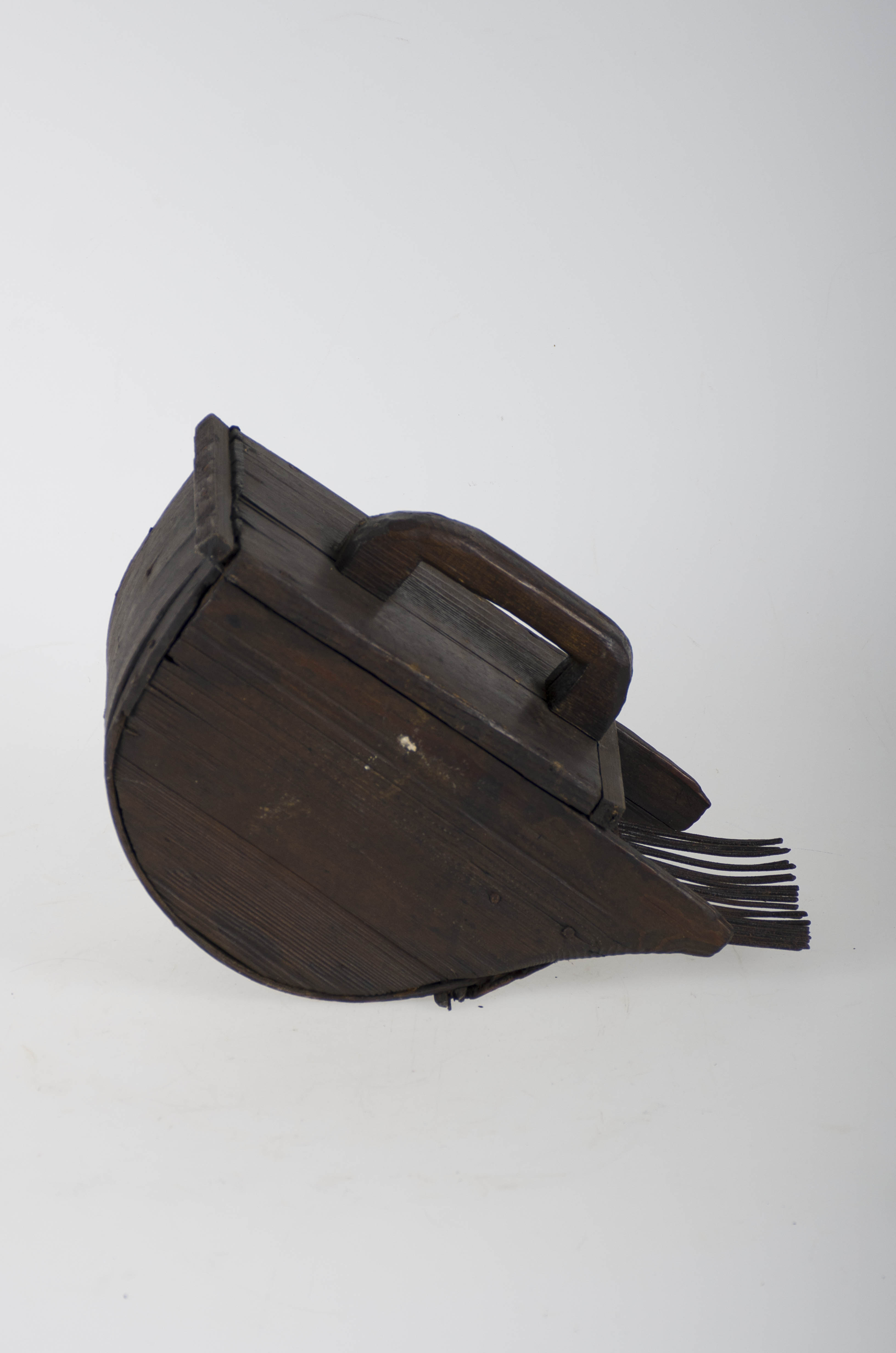 Piesă de formă semicirculară în secțiune, cu partea inferioară ce are aspectul unei cupe, din care pleacă 22 de cuie metalice de cca. 10 cm. Pe partea superioară este prevăzută cu un mâner pentru manipulare. Toate părțile sunt prinse cu cuie. Cromatică: maro închis/brun; negru.