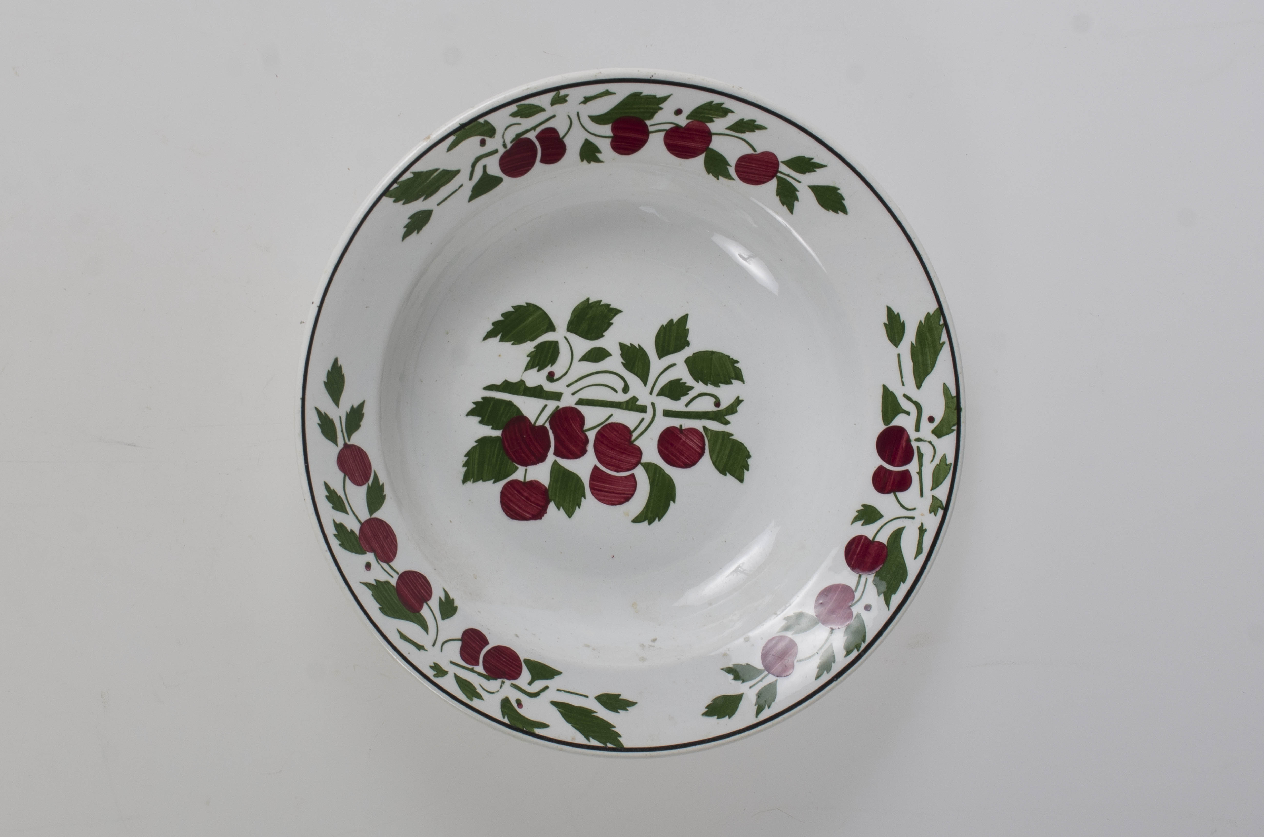 Farfurie de formă tronconică, adâncită; pe margine este decorat cu motive vegetale încadrate de o linie; în centru are o crenguță cu fructe (cireșe). Pe exterior la baza vasului prezintă trei cercuri concentrice și cifra ”26”. Cromatică: fond: alb; verde; roșu; negru. Pe fundul vasului sunt două incizii în care este introdus un șnur folosit la agățarea vasului pe perete.
