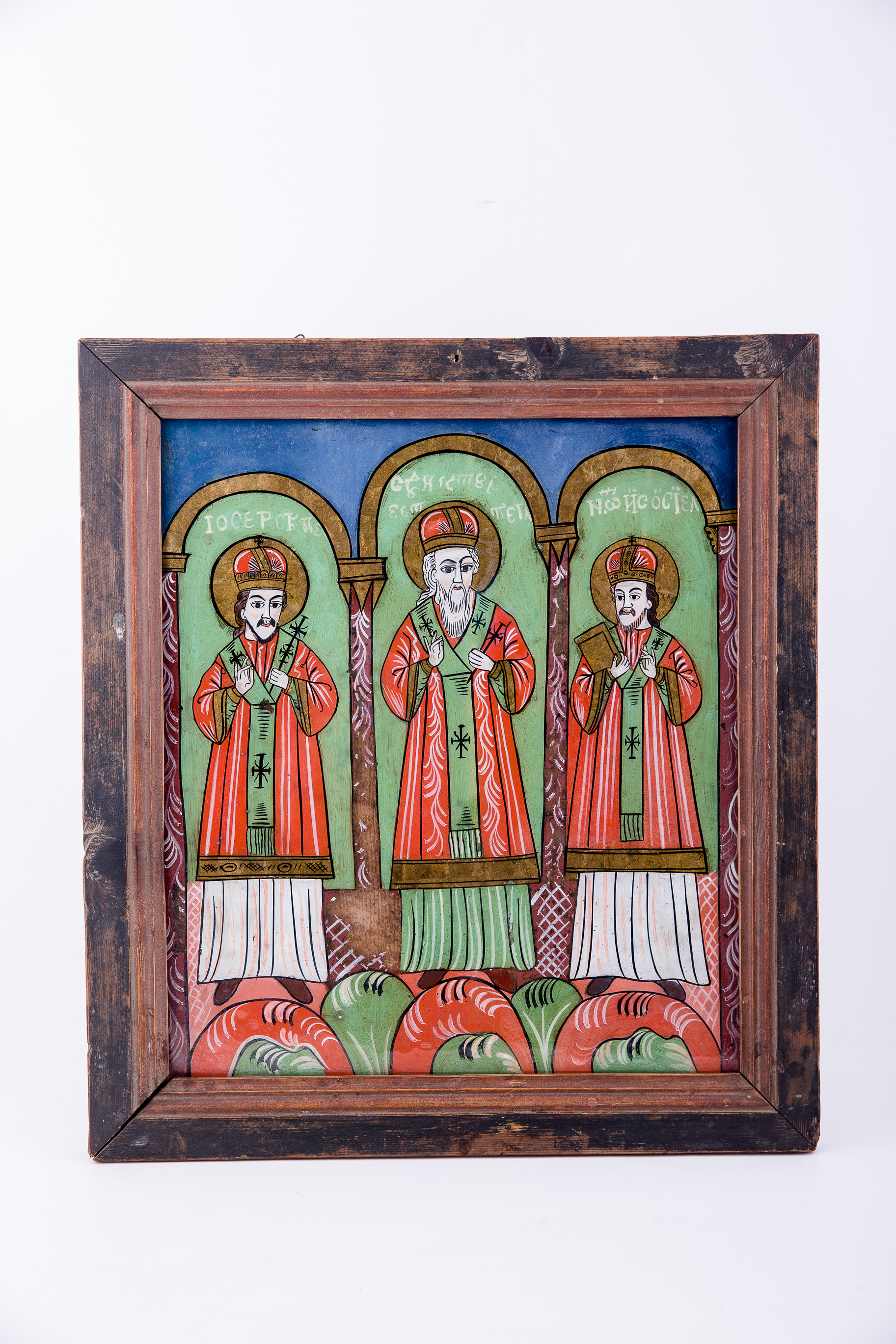 Cei Trei Sfinți Ierarhi Vasile cel Mare, Grigorie de Dumnezeu Cuvântătorul și Ioan Gură-de-Aur slujesc și săvârșesc Sfânta Liturghie împreună. Sunt înveșmântați în veșminte liturgice: sacos verde-alb-verde, felon roșu vermillon, epitrahil verde cu câte patru cruci. Sfântul Vasile cel Mare are Sfânta Evanghelie în mâna dreaptă. Sfântul Ierarh Grigorie de Dumnezeu Cuvântătorul Binecuvintează. Cei trei Sfinți Ierarhi stau cu picioarele pe perinițe rotunde de culori alternative: roșu, verde, alb. Fiecare sfânt ierarh este încadrat de două coloane și o boltă de biserică. Sunt prezente elemente arhitectură bisericească. Fondul registrului superior este albastru. Cromatica este luminoasă și armonioasă: verde, alb, roșu vermillon, roșu, albastru, negru. Este o icoană specifică picturii de Țara Făgărașului, cu un desen fin cu conturul negru și cromatica pastelată. După stilul picturii întregii compoziții, icoane poate să aparțină lui Matei Țimforea.