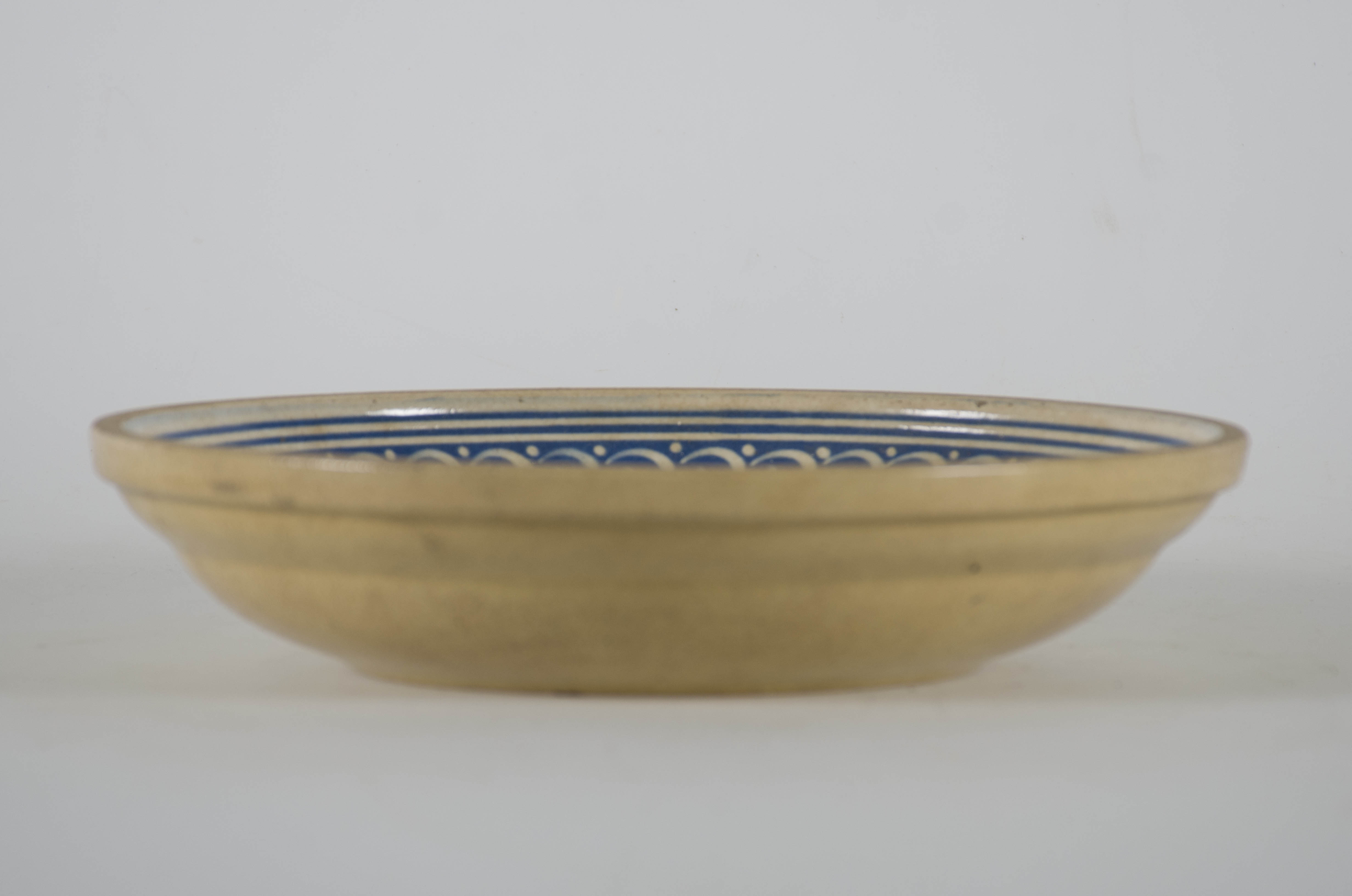 Vasul ceramic de formă tronconică este lucrat la roata rapidă. Este ușor adâncit având la interior un smalț albastru pe care sunt realizate motivele decorative geometrice dispuse în registre formate de cercuri concentrice: zale și puncte. La exterior vasul prezintă un smalț crem. Cromatică: crem; albastru; alb.