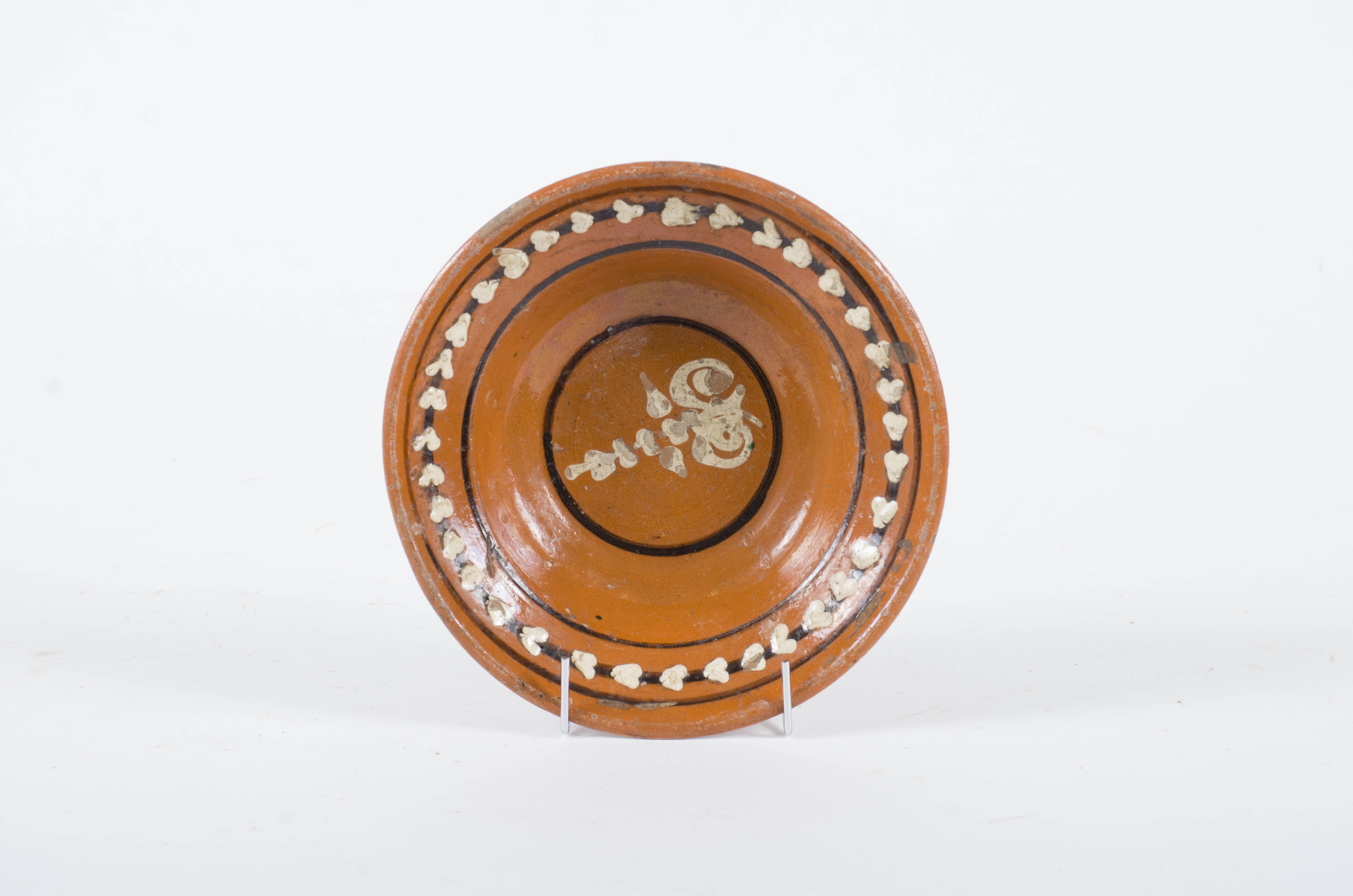 Vasul ceramic este de formă tronconică. Prezintă decor central: motive florale stilizate și cercuri concentrice. Pe margine sunt dispuse frunze si cercuri concentrice. Cromatică: fond: cărămiziu; motive: maro închis; alb.