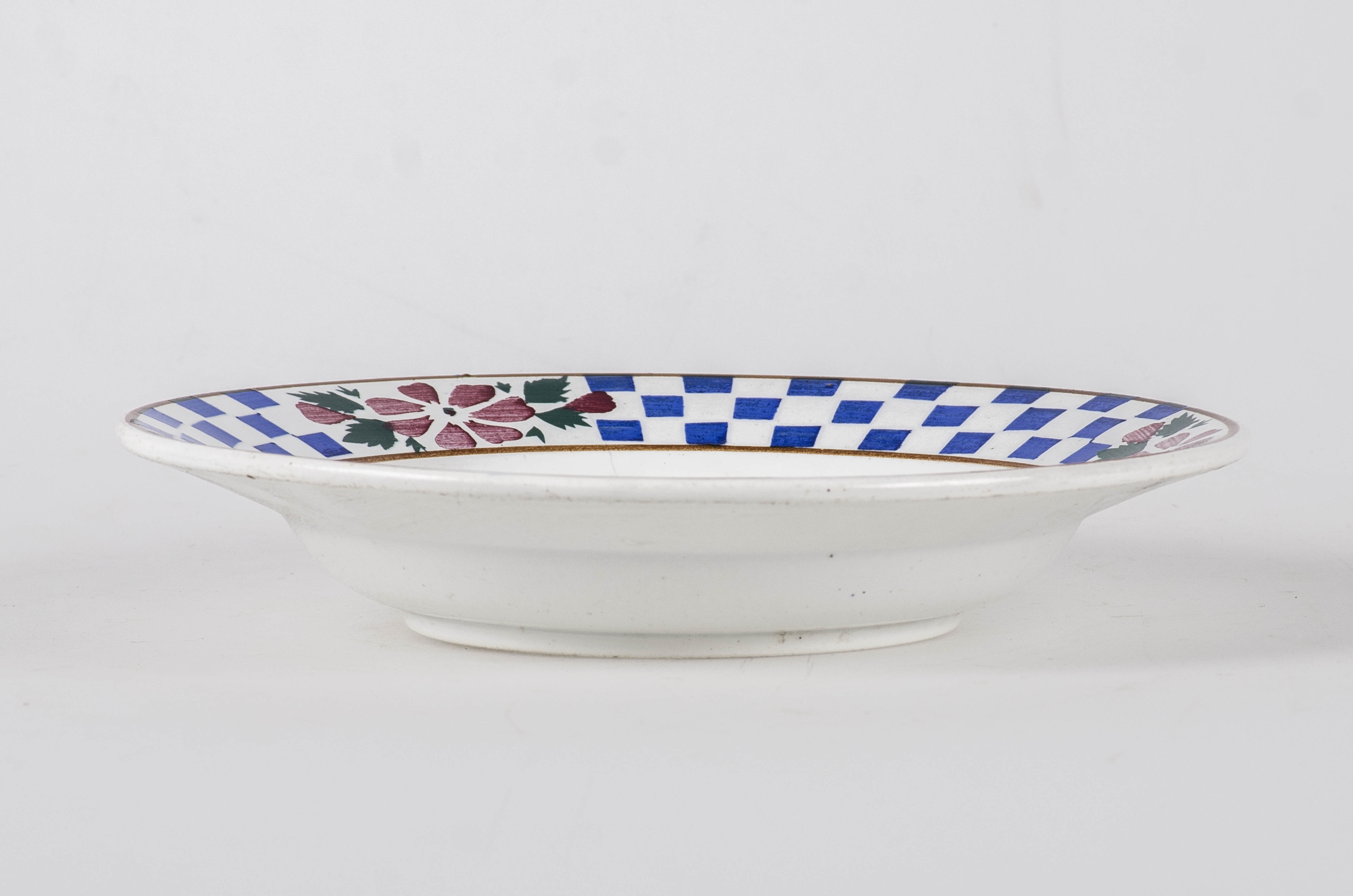 Ceramică de formă circulară prevăzută cu inel de susținere. Interiorul este decorat cu grupe de trei trandafiri roșii cu frunze de culoare verde deschis pe fundal alb. Pe margine, între două cercuri concentrice maro sunt trei flori roșii cu frunte verzi și boboci; pe suprafața dntre ele se întâlnește o "tablă de șah" în culorile albastru - alb. Cromatică: fond: alb; motive: albastru; verde; roșu.
