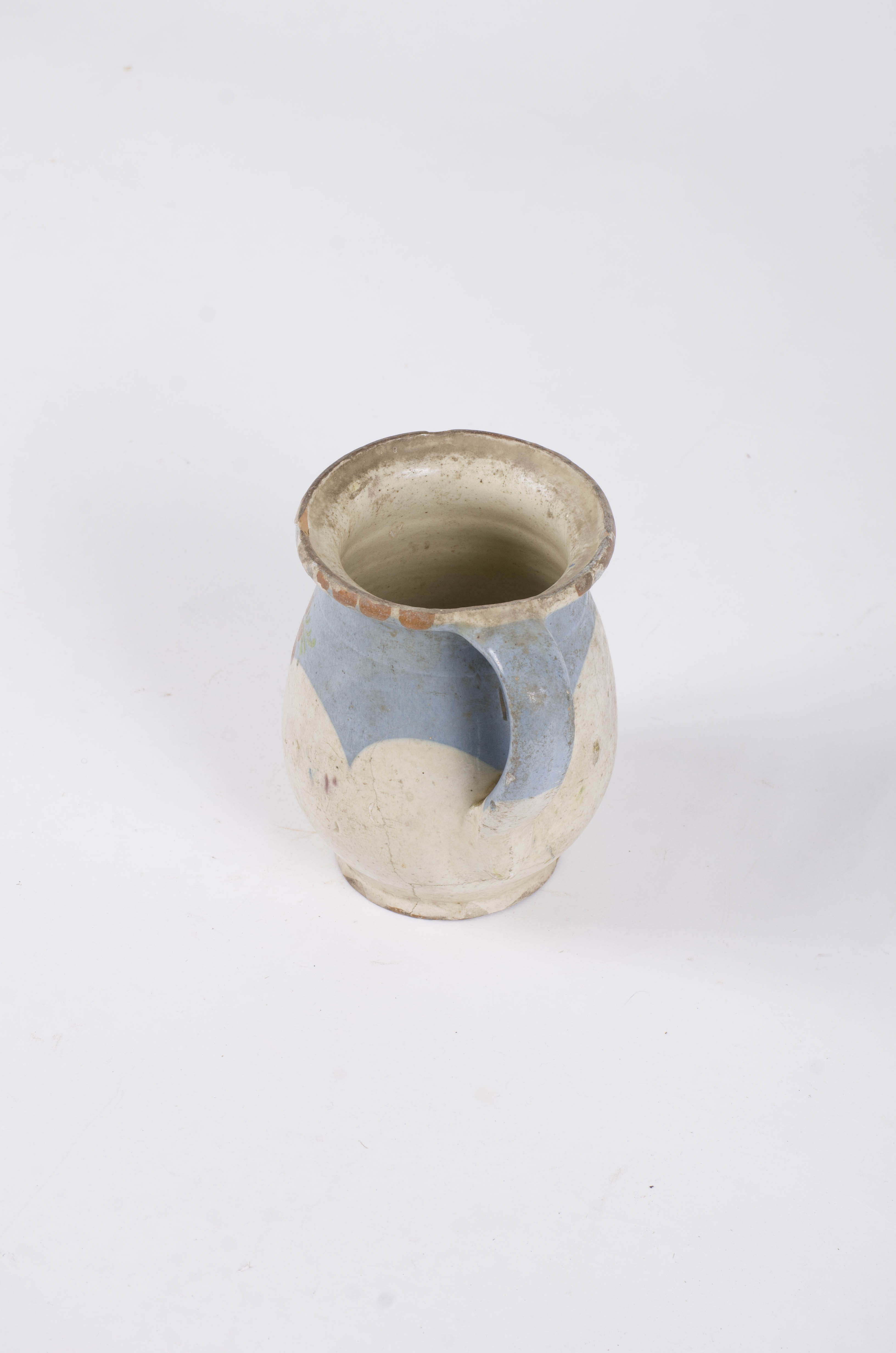 Vas ceramic de de formă ovoidală, puternic bombată în zona mediană, buza fiind îngroșată și răsfântă. Este prevăzută cu o toartă dispusă vertical de la buză spre zona mediană a vasului. Decorul pornește de sub buză spre centru vasului realizat cu tipar. De asemnea pe fondul smalțului alb se identifică un registru decorativ floral-vegetal. Toarta este decorată pe aproape întreaga suprafață. Decorul este obținut prin pictare. Cromatică: smalț alb; motive: albastru; maro; verde.