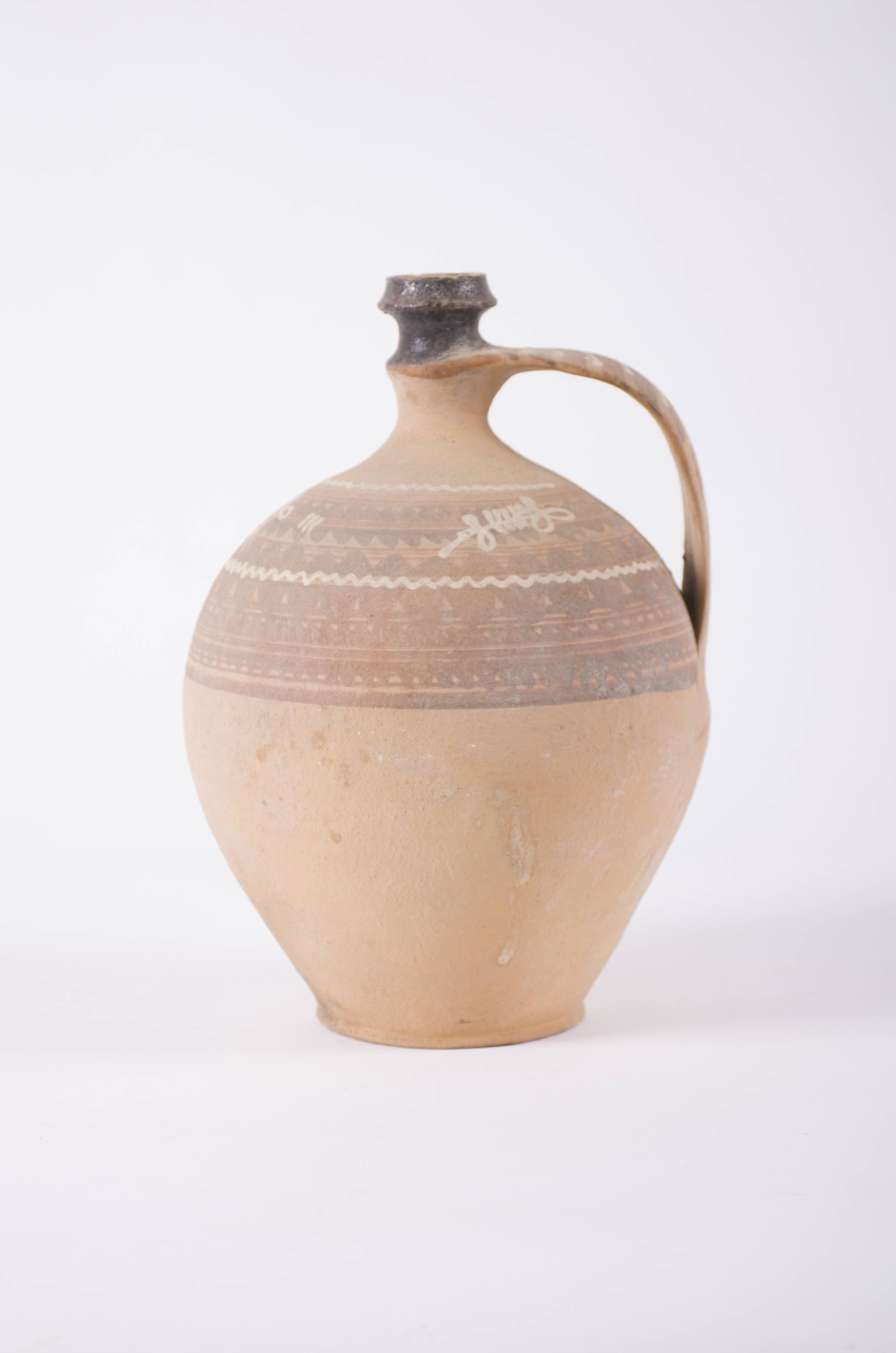 Recipientul ceramic are formă sferoidală și un gât și o gură îngustă. Prezintă o toartă laterală și decor pe umeri: motive geometrice: (linie vălurită, linii concentrice și paralele), motive vegetale (frunze stilizate). Gura vasului este smălțuită. Cromatică: fond: cărămiziu; motive: negru; alb.