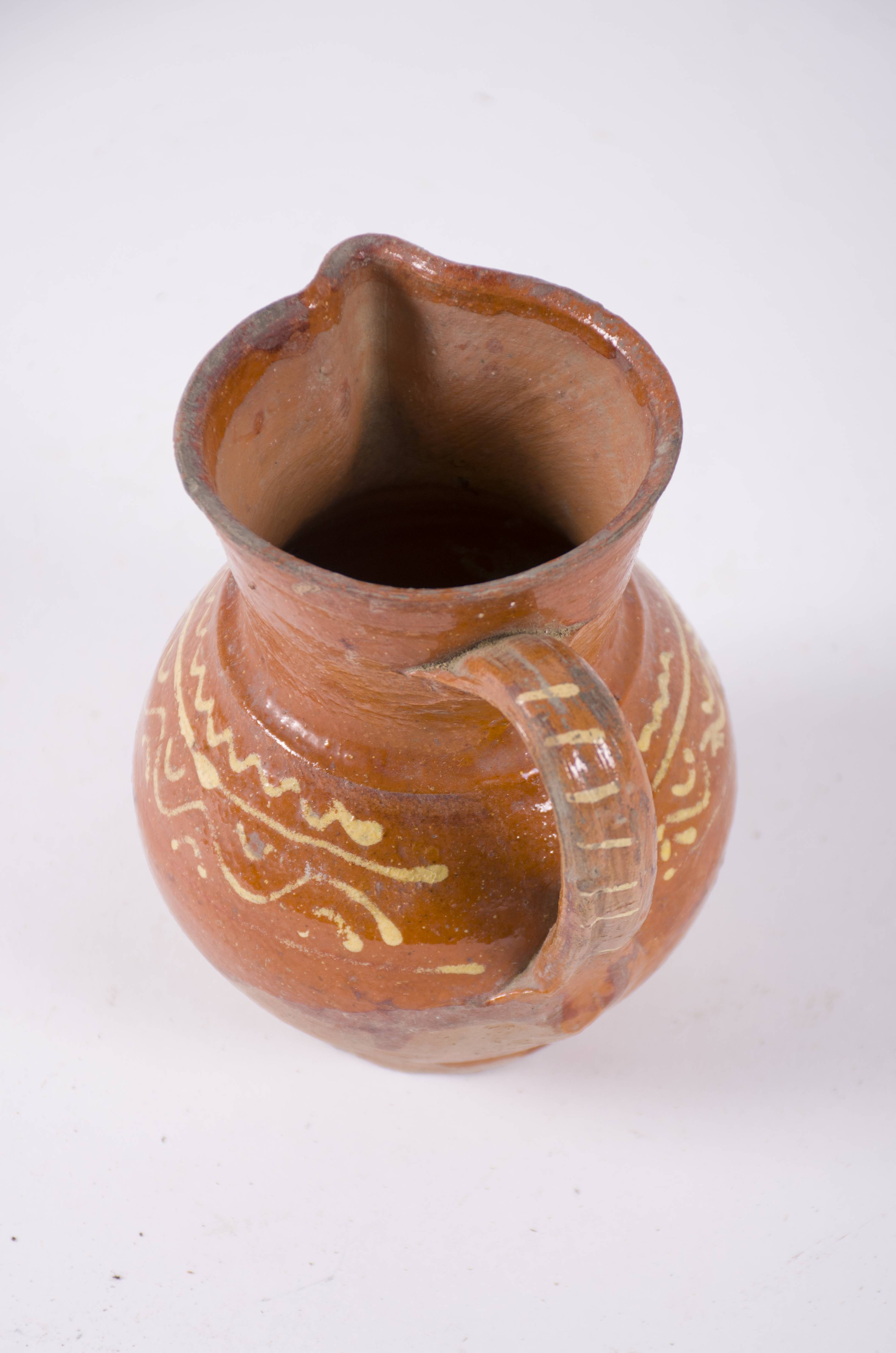 Vasul ceramic are corpul bombat și un gât foarte înalt. Prezintă o buză evazată și cioc pentru scurgere; opus ciocului prezintă o toartă ce pleacă din zona gâtului și se unește cu corpul în zona diametrului maxim. Piesa este smălțuită pe 3/4 din partea superioară. Este decorat în zona diametrului maxim cu motive geometrice: val, linie și arc de cerc. Pe toartă este decorată cu linii orizontale paralel. Cromatică: fond: cărămiziu, motive: alb.