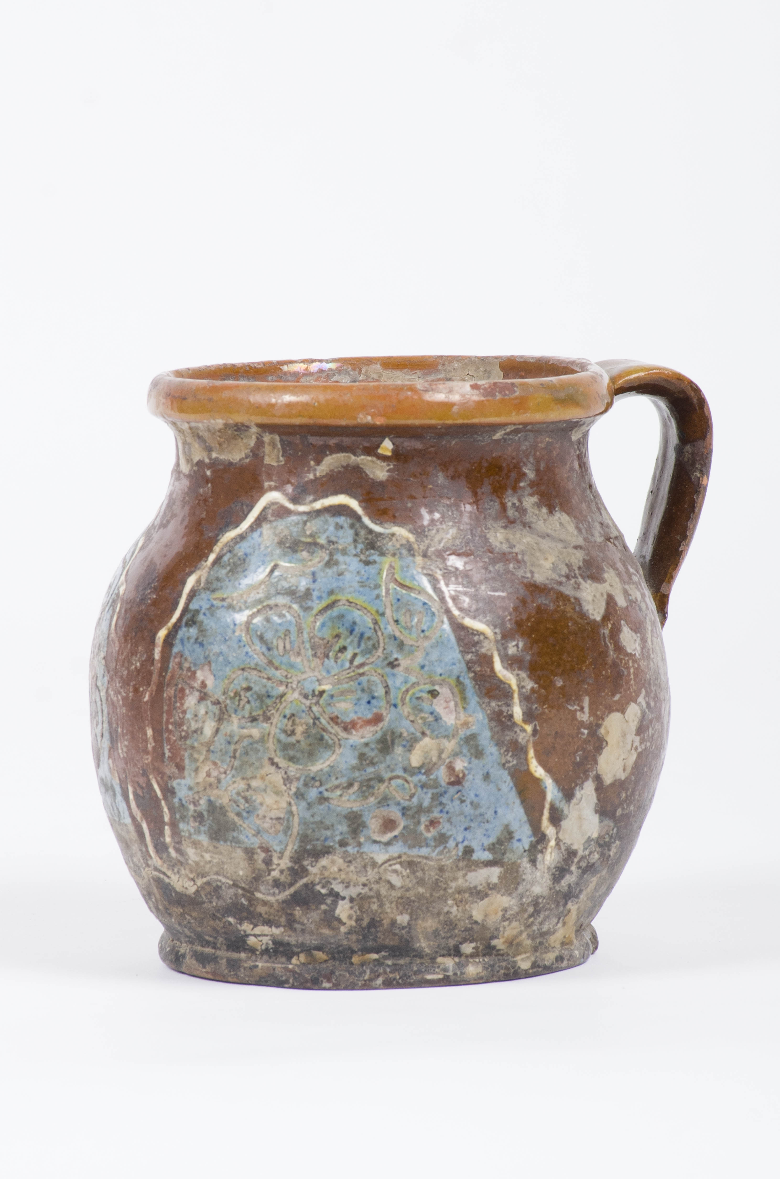 Vas ceramic de formă ovoidală cu gât lung și buza evazată. Ulcica prezintă o toartă care leagă buza vasului de pântec. Baza vasului este dreaptă și ieșită ușor înafară. Smălțuită în interior și exterior. Este decorată cu motive florale și vegetale (pe un fond albastru) încadrate de o linie în val. Cromatică: fond: maro; motive: albastru; verde; alb. Prezintă uzură funcțională.