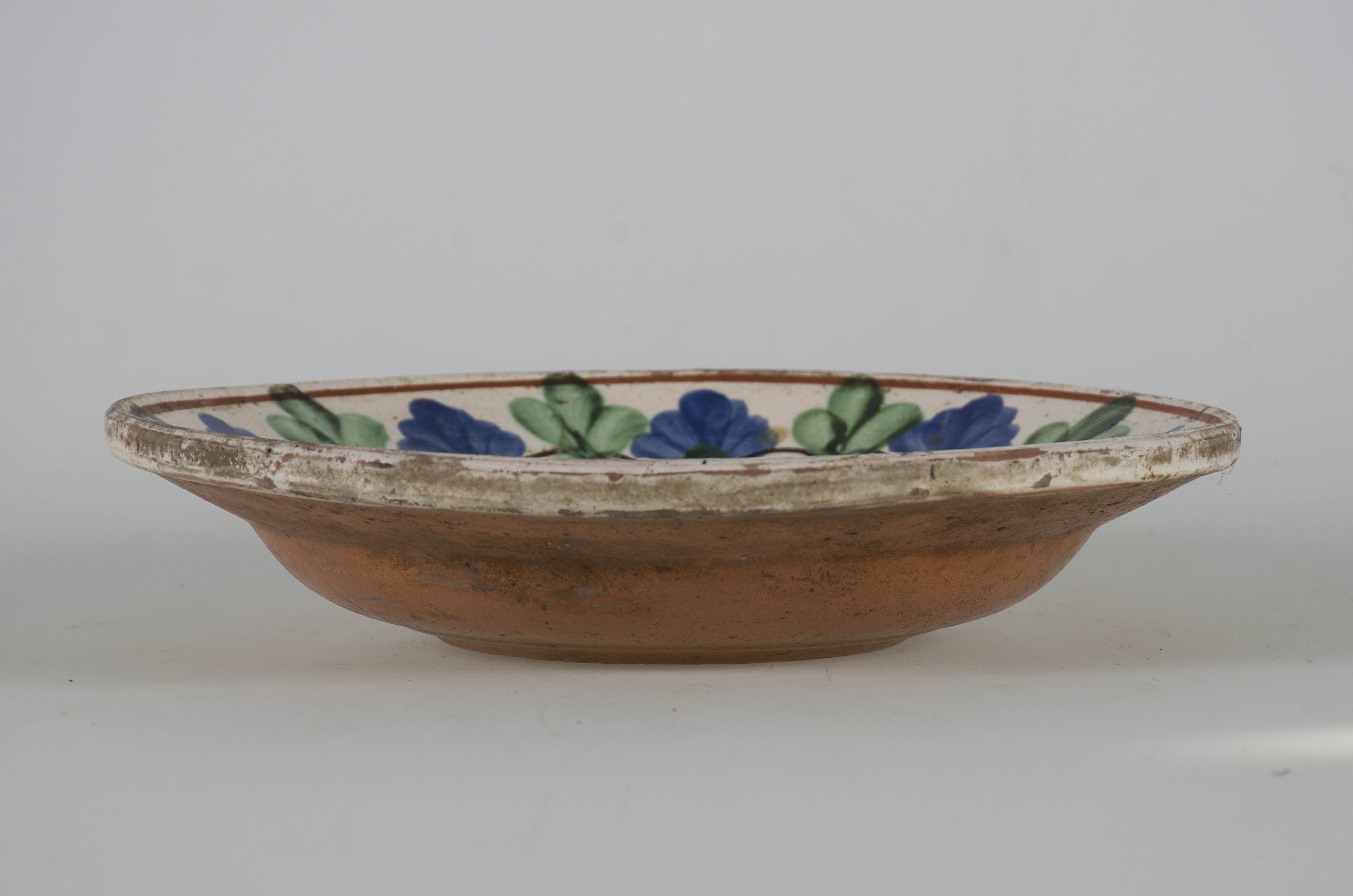 Vasul ceramic este de formă circulară, adâncit și cu marginile evazate. Este smălțuit în interior și pe buza exterioară a vasului. În interior, pe margine, blidul este ornamentat cu motive florale dispuse între două cercuri concentrice de culoare roșie. Registru floral este tăiat pe mijloc de o linie vălurită neagră. Cromatică: fond: alb; motive: roșu; verde; albastru deschis; maro; negru. Prezintă orificiu pentru sfoară.