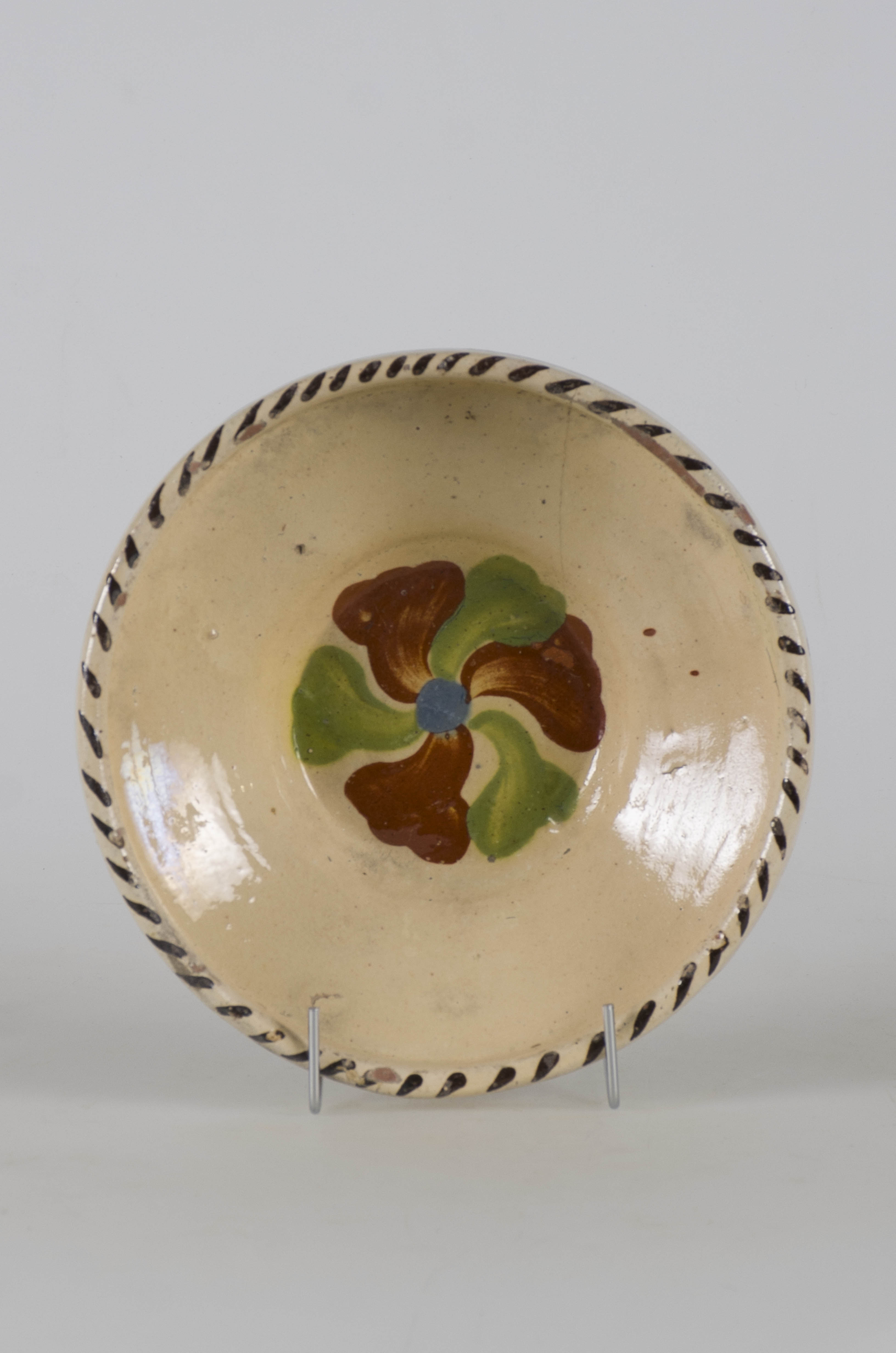 Vasul ceramic are formă tronconică și este prevăzut cu pereții evazați si o buza înaltă. Interiorul este smălțuit și la exterior doar la buză. Interiorul este ornamentat cu motive florale, iar buza cu linii. Cromatică: fond: alb; motive: maro; verde; albastru; negru.