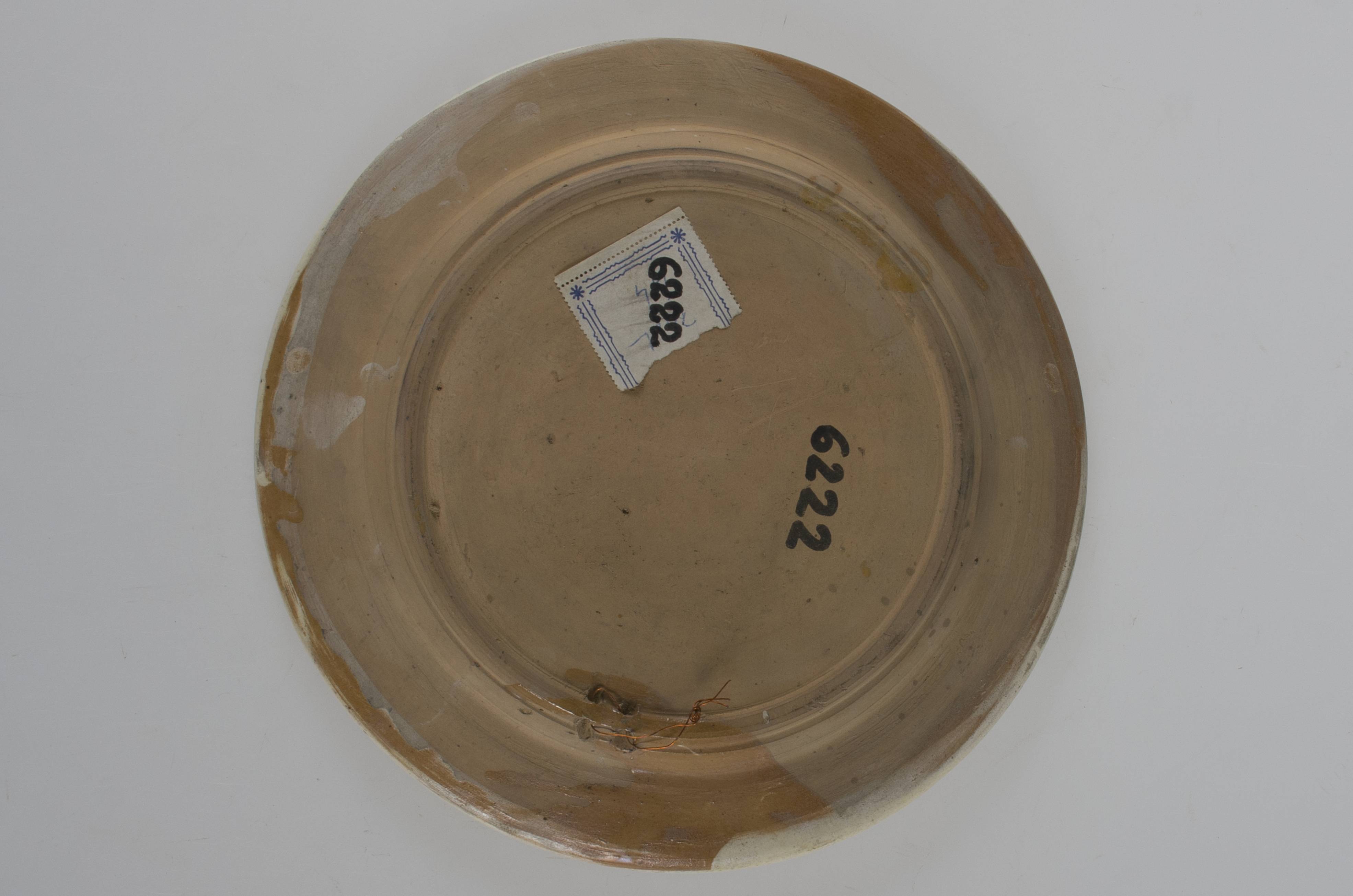 Vas ceramic tronconic cu orificiu de prindere; buza usor evazată. Decor geometric floral, zoomorf. Pe margini: șiruri de cercuri unite în formă de lanț; pe marginea interioară: cerc verde; motiv central: pasăre, frunze, lalea. Cromatică: motive: maron; galben; verde; pe fond: alb.