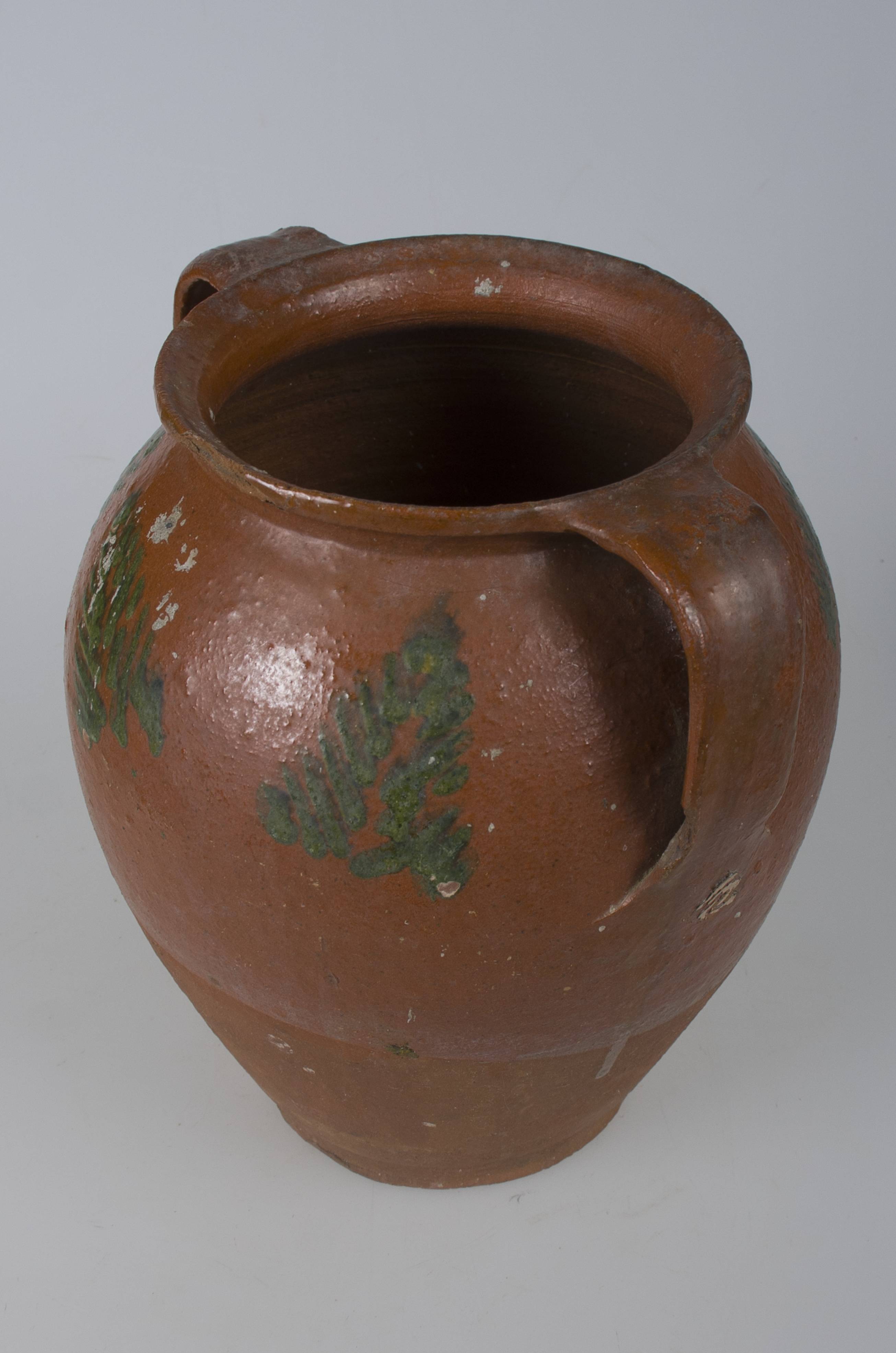 Vas ceramic bitronconic smălțuit, de mari dimensiuni, cu două toarte și realizat la roata olarului, uscat, pictat și apoi ars. Cele două toarte poziționate de-o partea și cealaltă a vasului, pornesc de la buza vasului spre diametrul maxim al acestuia. Vasul prezintă un decor vegetal stilizat, în mod special în partea superioară, compus dintr-un registru concentric format din trei brazi de culoare verde. Buza vasului prezintă o o „îndoitură” în dreapta toartei, realizată cel mai probabil pentru folosirea la nevoie a unui capac. Cromatică: fond: cărămiziu; motive: verde.