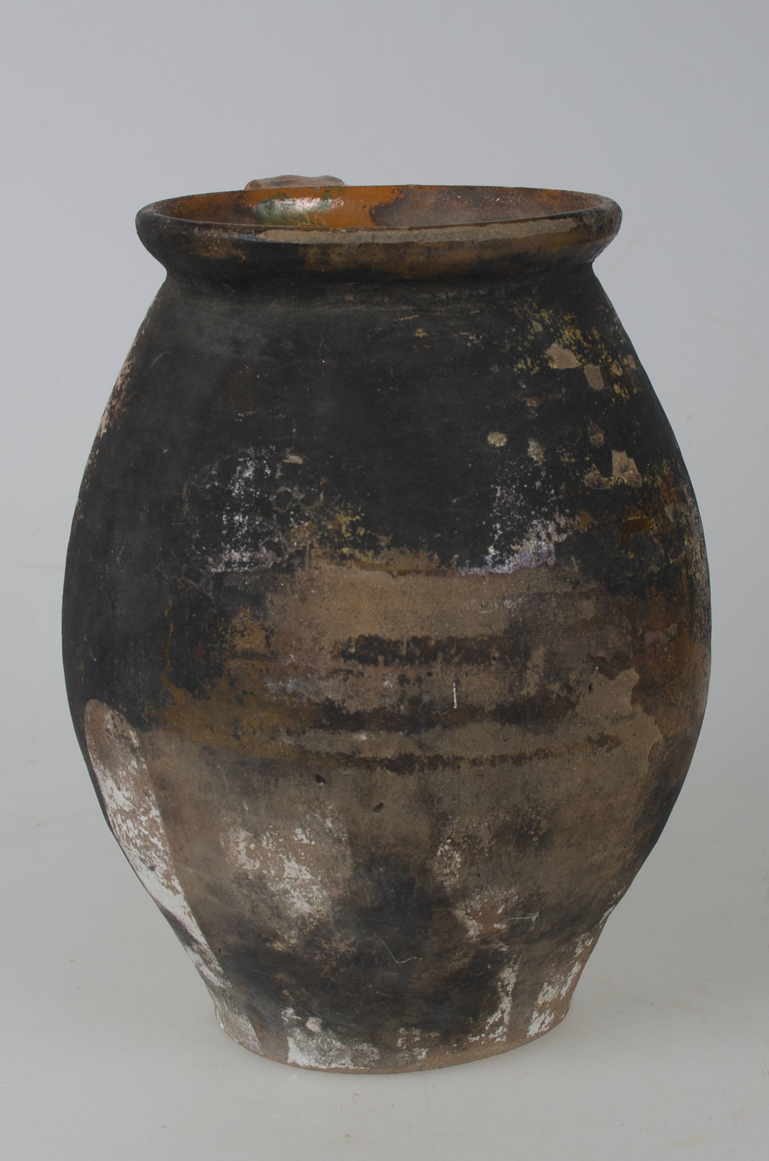 Vas ceramic smălțuit de dimensiuni medii, realizat la roata olarului, uscat, pictat, apoi ars și smălțuit. Oala, prezintă o toartă, care pornește de la buza vasului spre diametrul maxim al acestuia. Vasul prezintă un decor vegetal simplu, compus pete de culoare suprapruse - galben. În jumătatea inferioară a vasului zece dungi de culoare albă, pornesc de la diametrul maxum al vasului spre bază. Cromatica vasului este maro deschis, iar cea a decorului pictat este alb, verde și galben. Sunt vizibile urme de funingine, cauzate de folosirea excesivă la foc dechis.