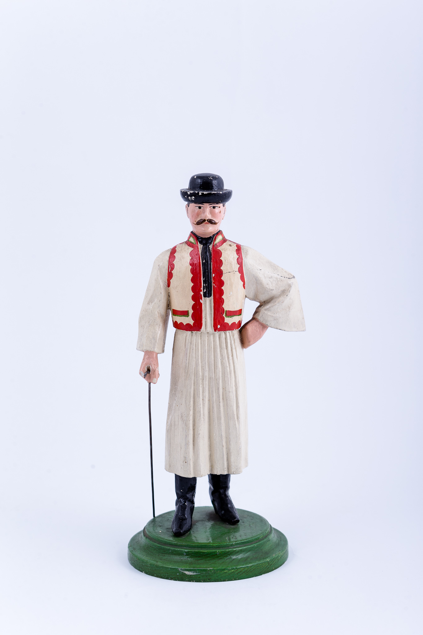 Statuetă de lemn, acoperită cu ghips, pentru a ascunde eventualele fisuri. Statueta reprezintă o figură masculină și este fixată pe un postament de culoare verde. Statueta este pictată, reproducând un bărbat îmbrăcat în port popular maghiar din zona Călatei. Portul redat prin pictură este compus din cizme negre, pantaloni largi de culoare neagră, cămașă cu mânecă largă, pieptar descheiat în față, cravată neagră și pălărie neagră. În mâna dreaptă bărbatul ține un baston metalic. Cromatică: verde, roșu, alb, negru.
