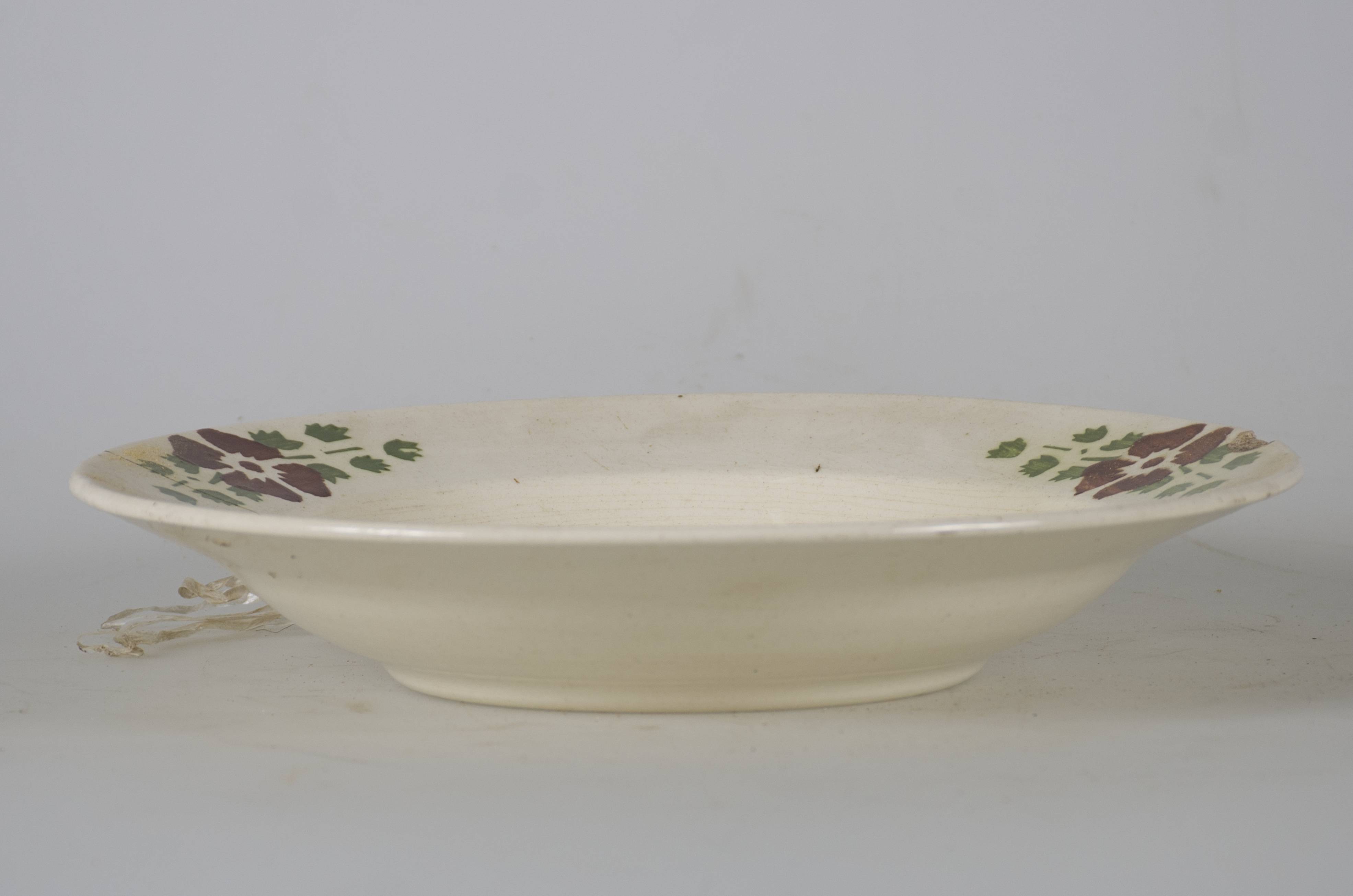 Vas ceramic smălțuit, de formă tronconică, cu marginile puțin ridicate și fundul plat. Pe fond alb sunt prezente decorații realizate în registru floral-vegetal, ilustrând un grup de trei flori albastre (trandafiri) cu frunze verzi, aflat pe fundul vasului. Pe marginea vasului sunt dispuse trei flori cu petale maro închis și frunze verzi. Pe spate, la bază, prezintă două perforații pentru suspendare. Cromatică: fond: alb; motive: albastru; verde; maro