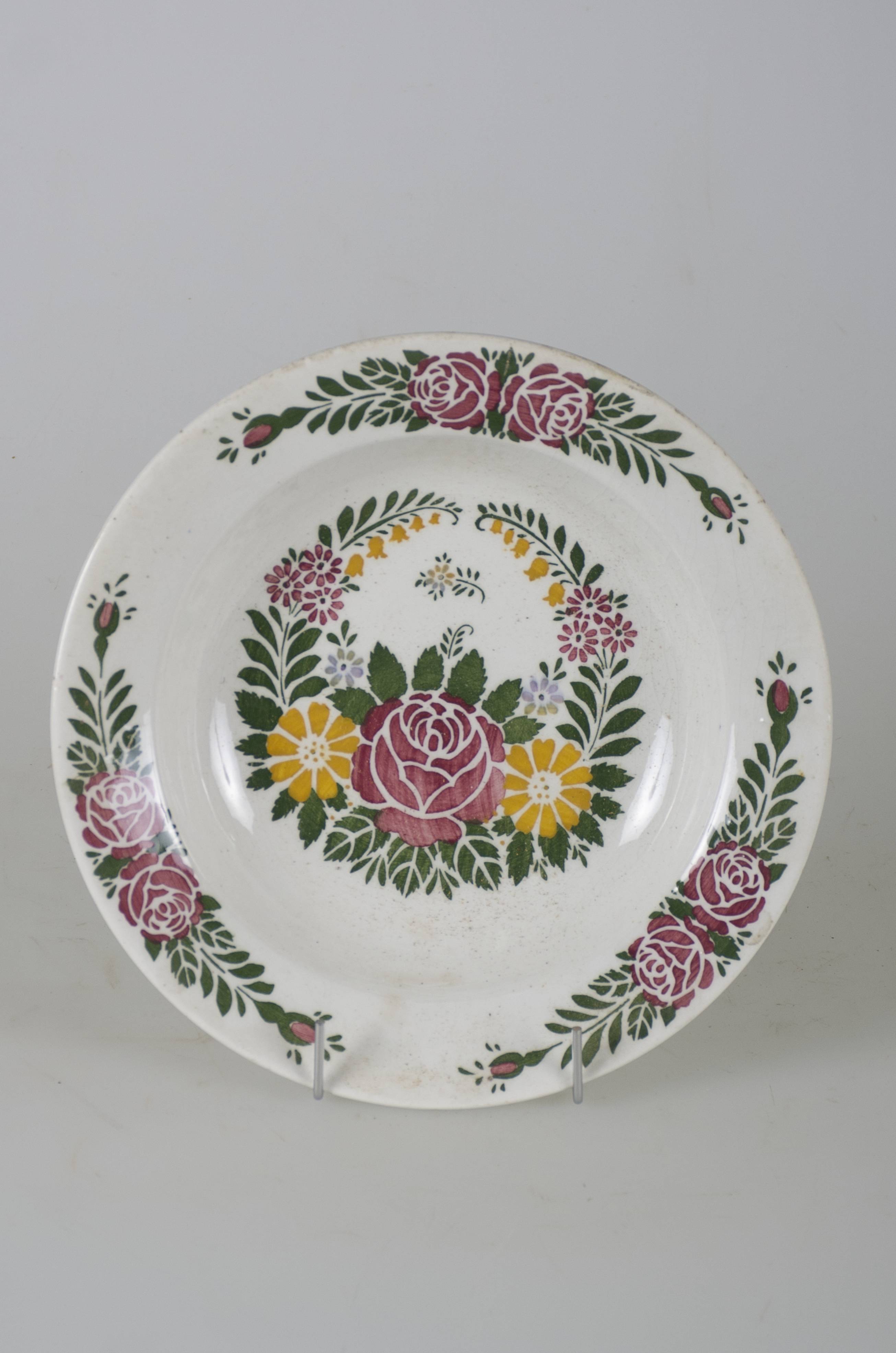 Vas ceramic smălțuit de formă tronconică cu marginile puțin ridicate și fundul plat. Pe fond alb avem decorații în registru floral-vegetal ilustrând o cunună ce are la bază un trandafir roșu încadrat de două flori galbene, cu frunze verzi și galbene și câte două grupe a câte trei flori de mici dimensiuni. Pe marginea vasului sunt dispuse trei registre cu câte doi trandafiri roșii fiecare, frunze verzi și câte doi boboci roșii. Pe spate prezintă două orificii pentru suspendare.