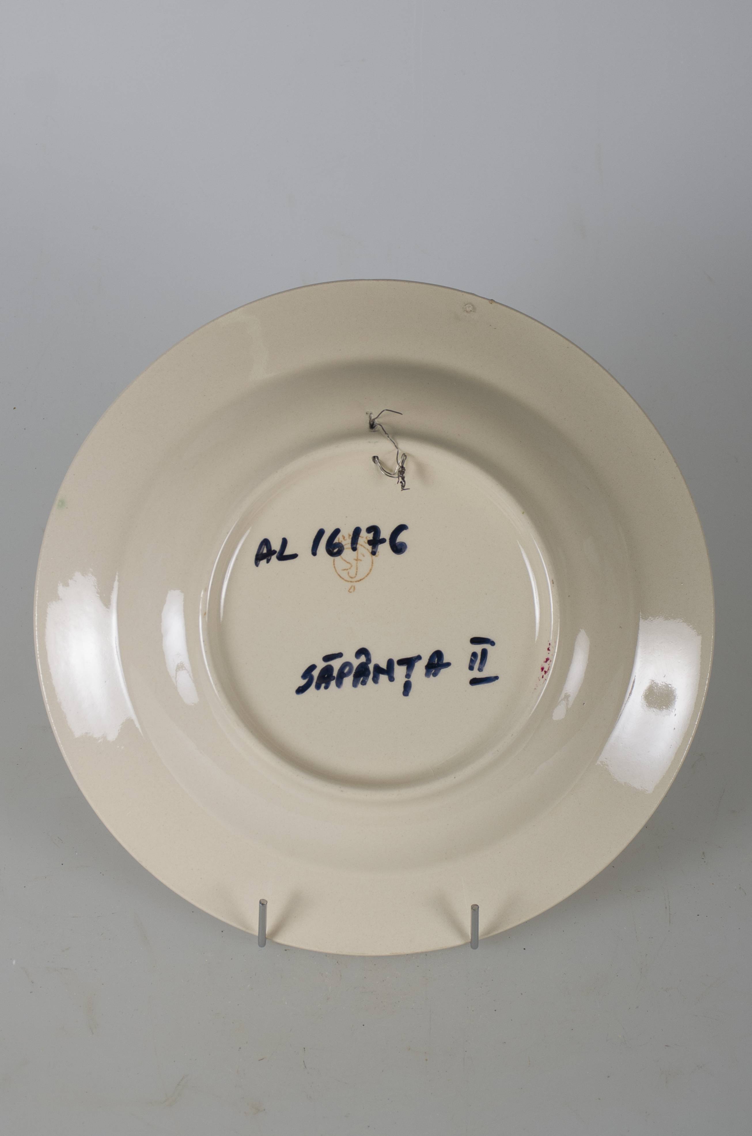 Vas ceramic smălțuit, de formă tronconică, cu marginile puțin ridicate și fundul plat. Pe fond alb avem decorații pictate în registru floral-vegetal, ilustrând trei flori roșii cu câte un cerc negru fiecare și frunze de culoare verde deschis. Marginile vasului conturate de două linii circulare roșii. Între cele două linii sunt dispuse flori albastre și roșii, despărțite de frunze în verde închis.