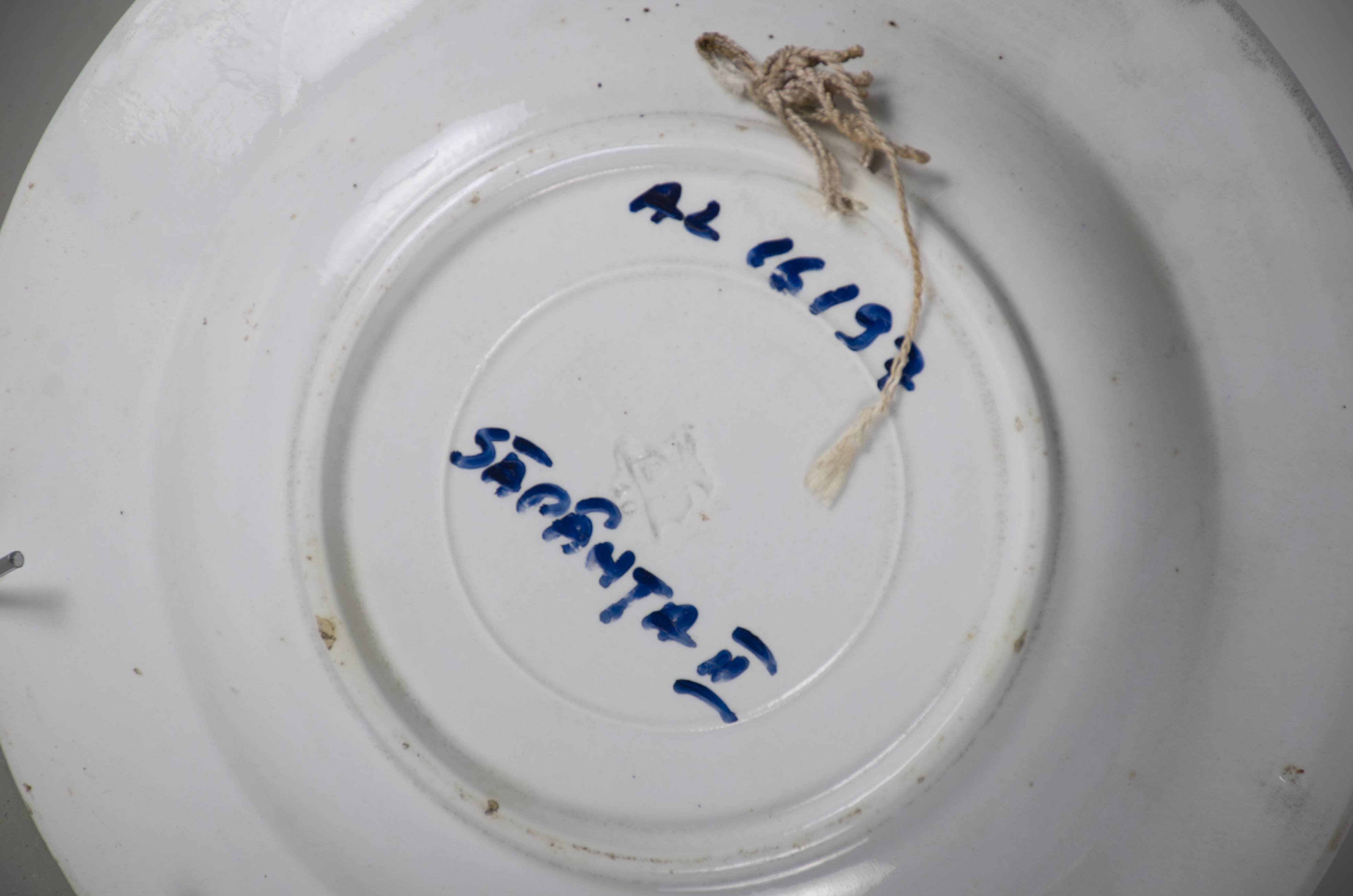 Vas ceramic smălțuit, de formă tronconică, cu marginile puțin ridicate și fundul plat. Pe fond alb decorații ilustrând trei flori roșii (bujori, maci) dispuse în formă de triunghi din care radiază frunze verzi și trei boboci roșii. Compoziția ocupă tot fundul vasului. Marginile vasului conturată de o bandă roșie subliniată de două linii negre circulare. Pe bandă suprapuse câte două grupe a câte două flori albastre cu frunze verzi și două grupe a câte o floare și un boboc roșu cu frunze verzi. Prezintă un orificiu, la bază, pe partea din spate, pentru a fi suspendată. Cromatică: fond: alb; roșu; motive: roșu; verde; negru; albastru.