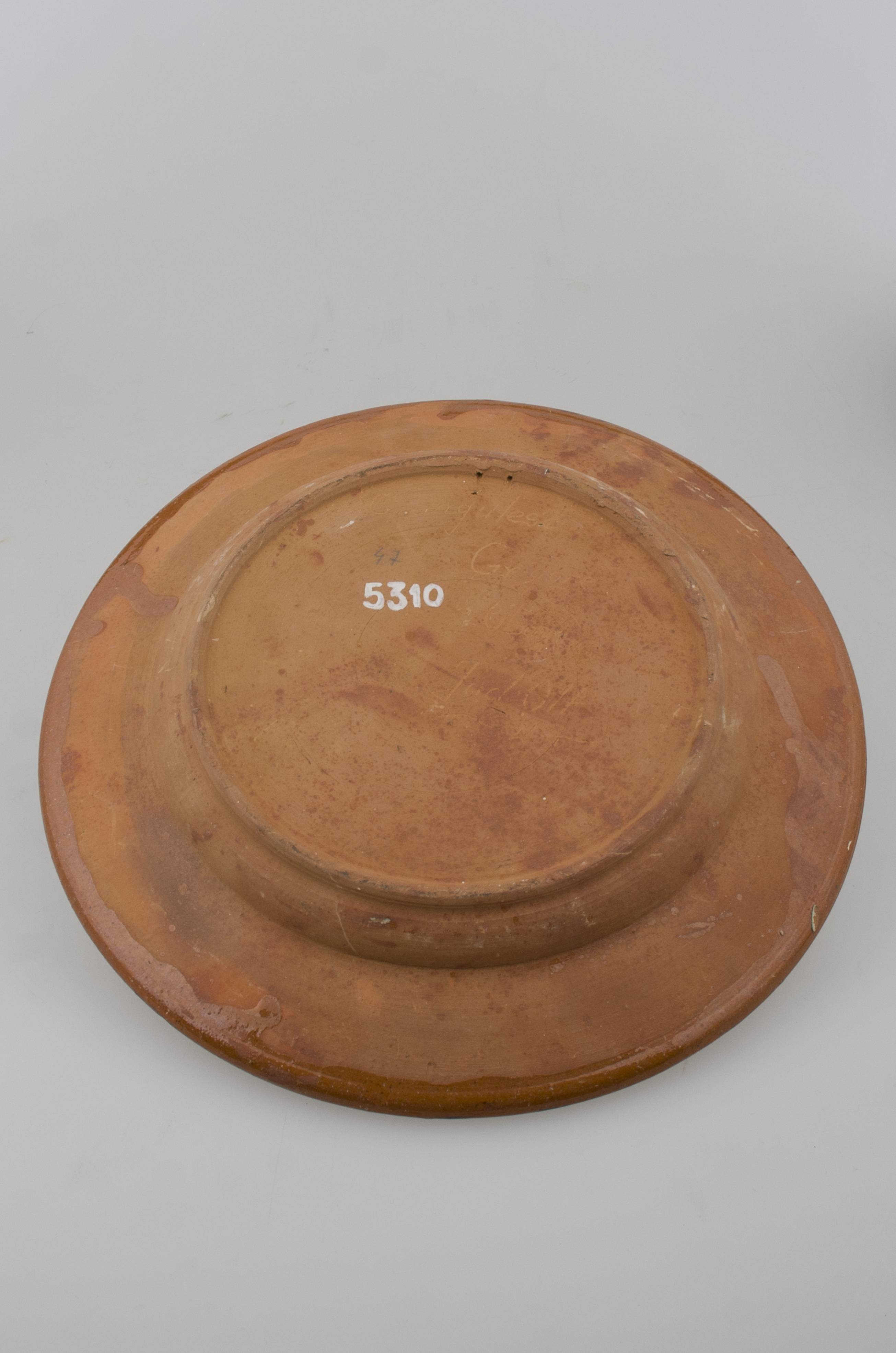 Blid tronconic cu fund plat, margine puțin ridicată și buza ușor oblică. Decor cu motive aviforme și florale: cocoș pe centru și o floare; pe margine, circular, motive geometrice (semicercuri, liniare, punctate, zig-zag). Cromatică: fond: cărămiziu; motive: maro; verde; alb; galben.