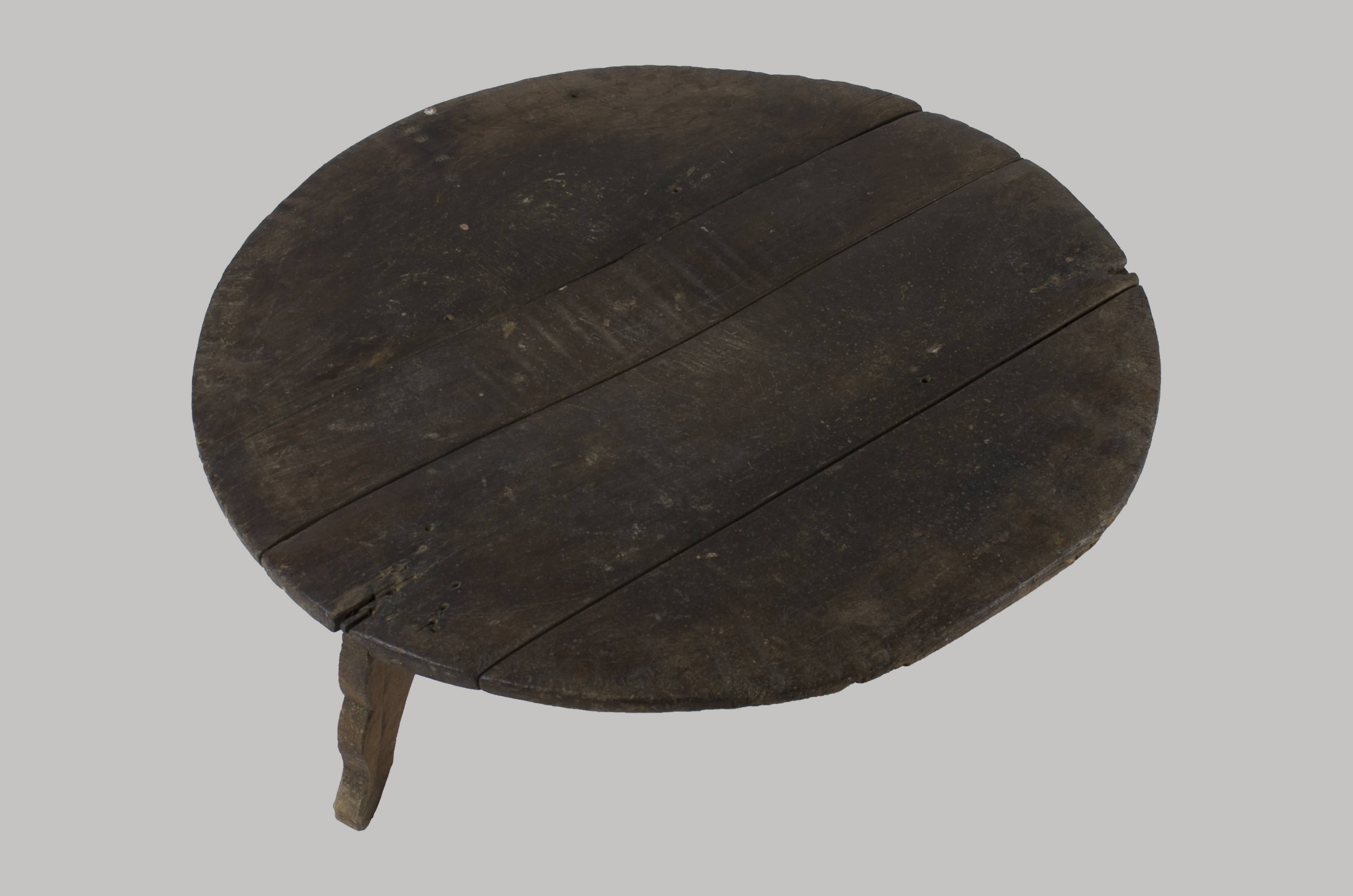 Masă de formă circulară cu tăblia formată din patru scânduri, sprijinită pe trei picioare scurte. Picioarele sunt ornamentate prin traforare (linii curbe). Cromatică: culoarea patinată a lemnului.