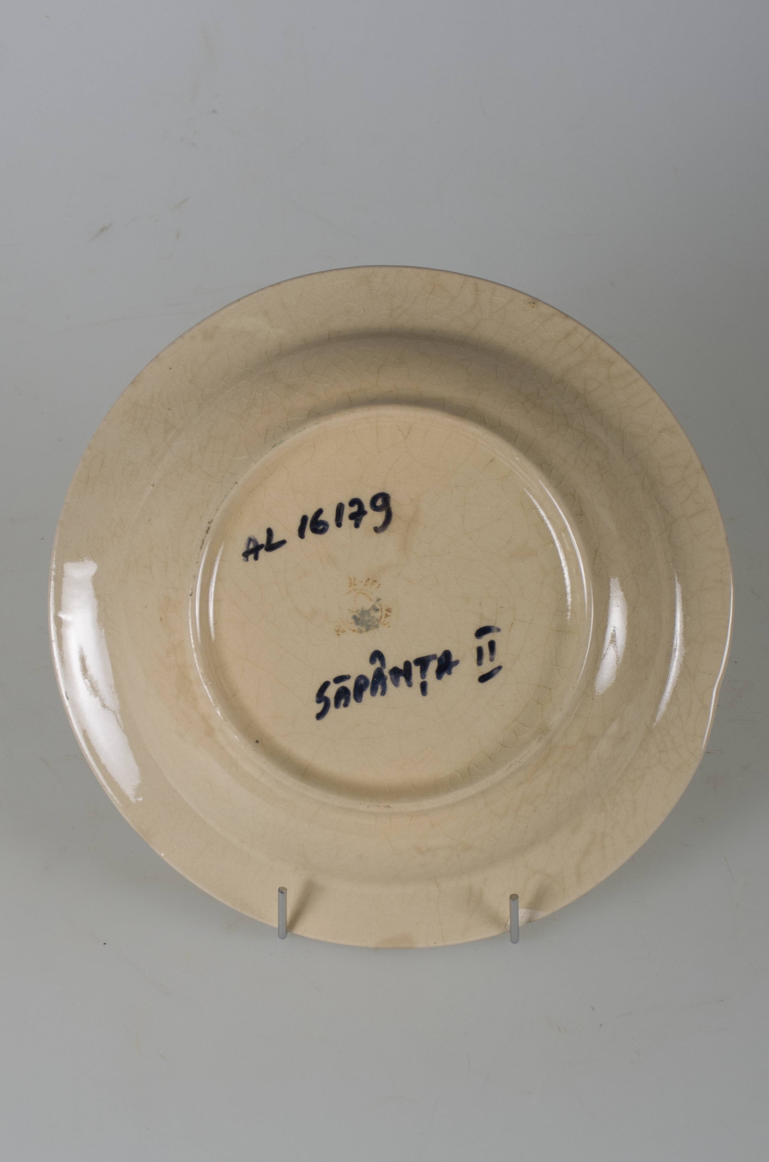 Vas ceramic smălțuit, de formă tronconică, cu marginile puțin ridicate și fundul plat. Pe fond alb-crem sunt decorații florale dispuse pe fund, central. Pe spate, la bază, prezintă două perforații pentru suspendare. Cromatică; fond: alb-crem; motive: verde; albastru; mov; galben; portocaliu.
