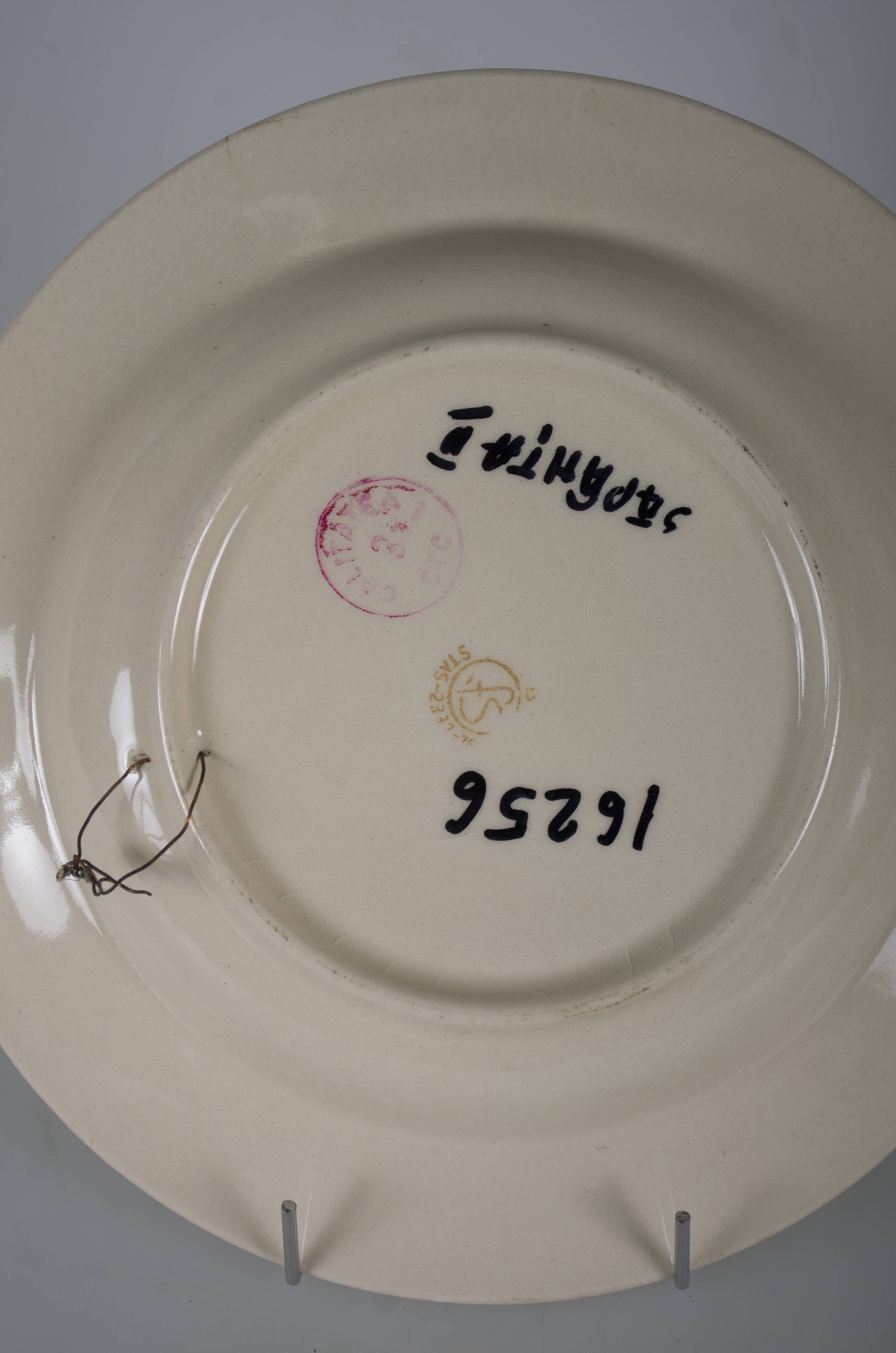 Vas ceramic smălțuit, de formă tronconică, cu marginile puțin ridicate și fundul plat. Pe fond alb decorații în registru floral-vegetal realizate în culoare albastră. Pe întreg fundul vasului compoziție având în centru un cerc plin împreună cu patru flori (bujori). Pereții interiori conturați de o bandă. Pe marginile vasului încadrate de două linii circulare decorații ilustrând câte patru frunze dispuse orizontal și petale dispuse vertical, separate de șiruri verticale a câte trei puncte dispuse pe diagonală. Cromatică: fond: alb, motive: albastru.