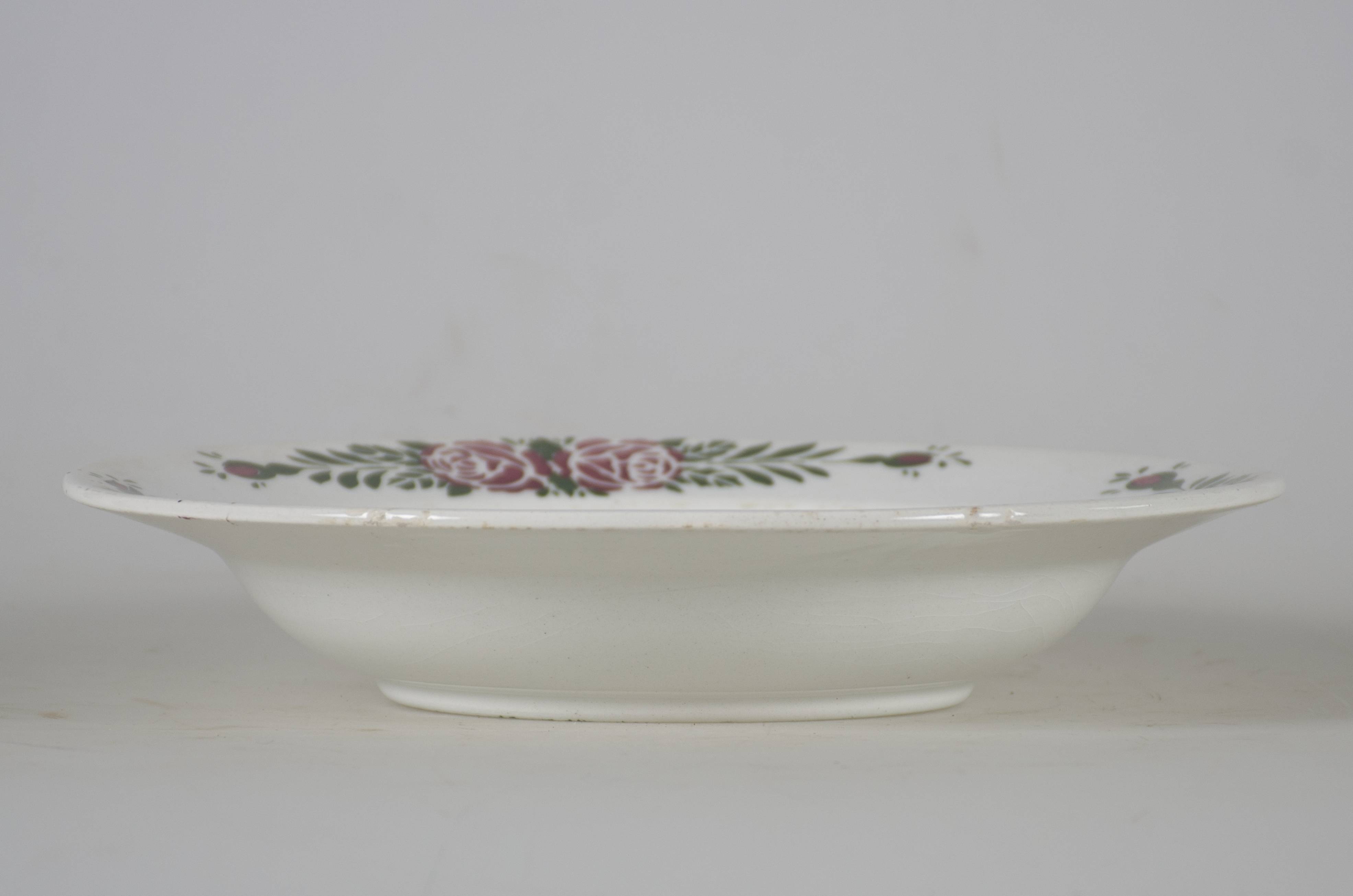 Vas ceramic smălțuit de formă tronconică și cu marginile puțin ridicate și fundul plat. Pe fond alb avem decorații în registru floral-vegetal ilustrând o cunună având la bază un trandafir roșu încadrat de două flori galbene, cu frunze verzi și câte două grupe a câte trei flori de mici dimensiuni. Pe marginea vasului dispuse trei registre cu câte doi trandafiri roșii fiecare, frunze verzi și câte doi boboci roșii. Pe spate prezintă un orificiu pentru suspendare. Pe dos sunt patru linii concentrice reliefate. Cromatică: fond: alb; motive: roșu; galben; verde.
