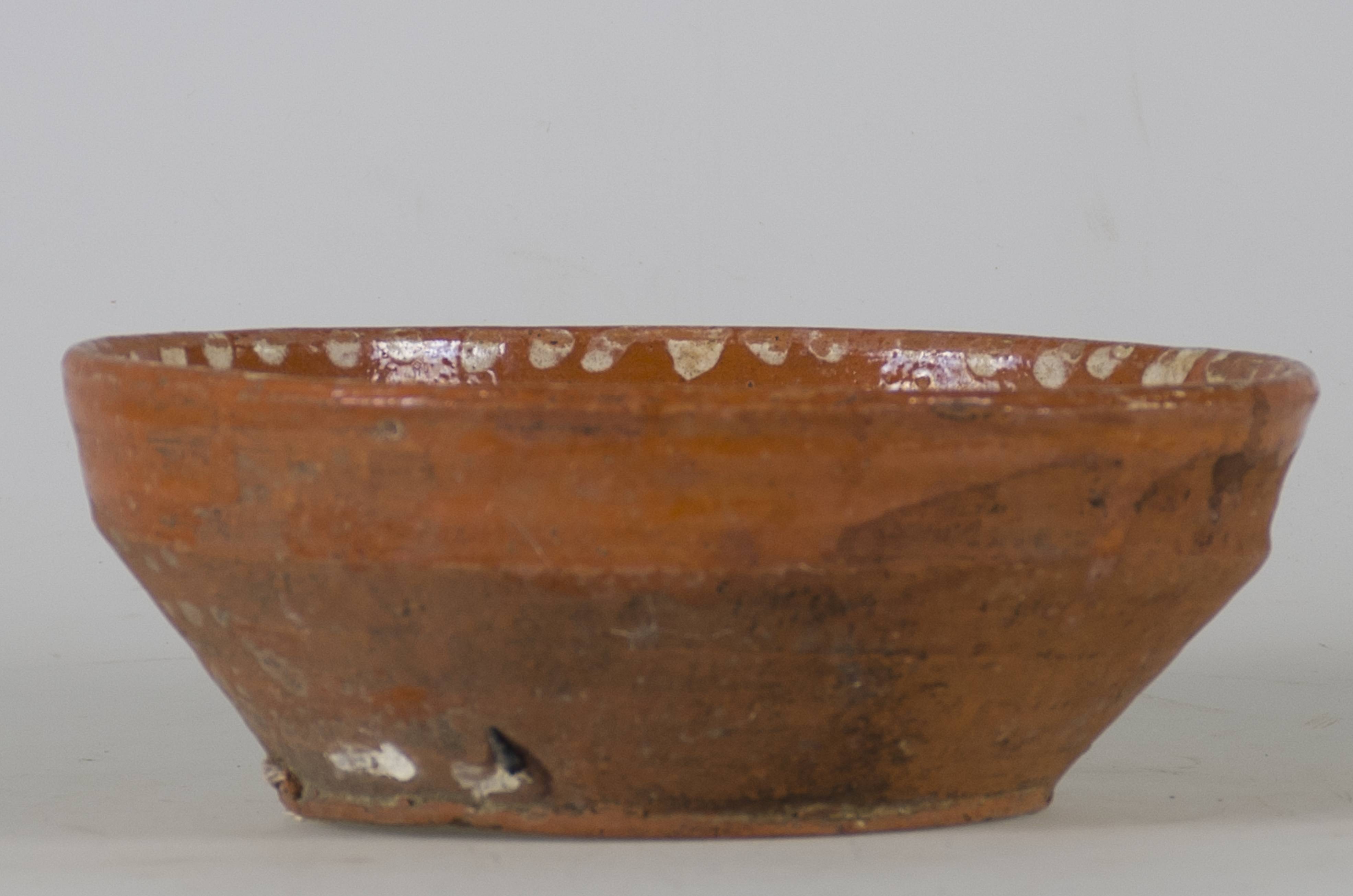 Vas ceramic smălțuit în interior, de formă tronconică, cu marginile puțin ridicate și fundul plat. Pe fond maro deschis prezintă decorații realizate prin pictare în registru floral-vegetal, ilustrând o floare cu șase petale albe pe fundul vasului și șase flori albe de mai mici dimensiuni despărțite de frunze verzi, dispuse pe pereții interiori ai vasului. Pe buza farfuriei șir de puncte albe. Pe spate, la bază, prezintă două orificii pentru suspendare. Cromatică: fond: maro; motive: alb; verde.