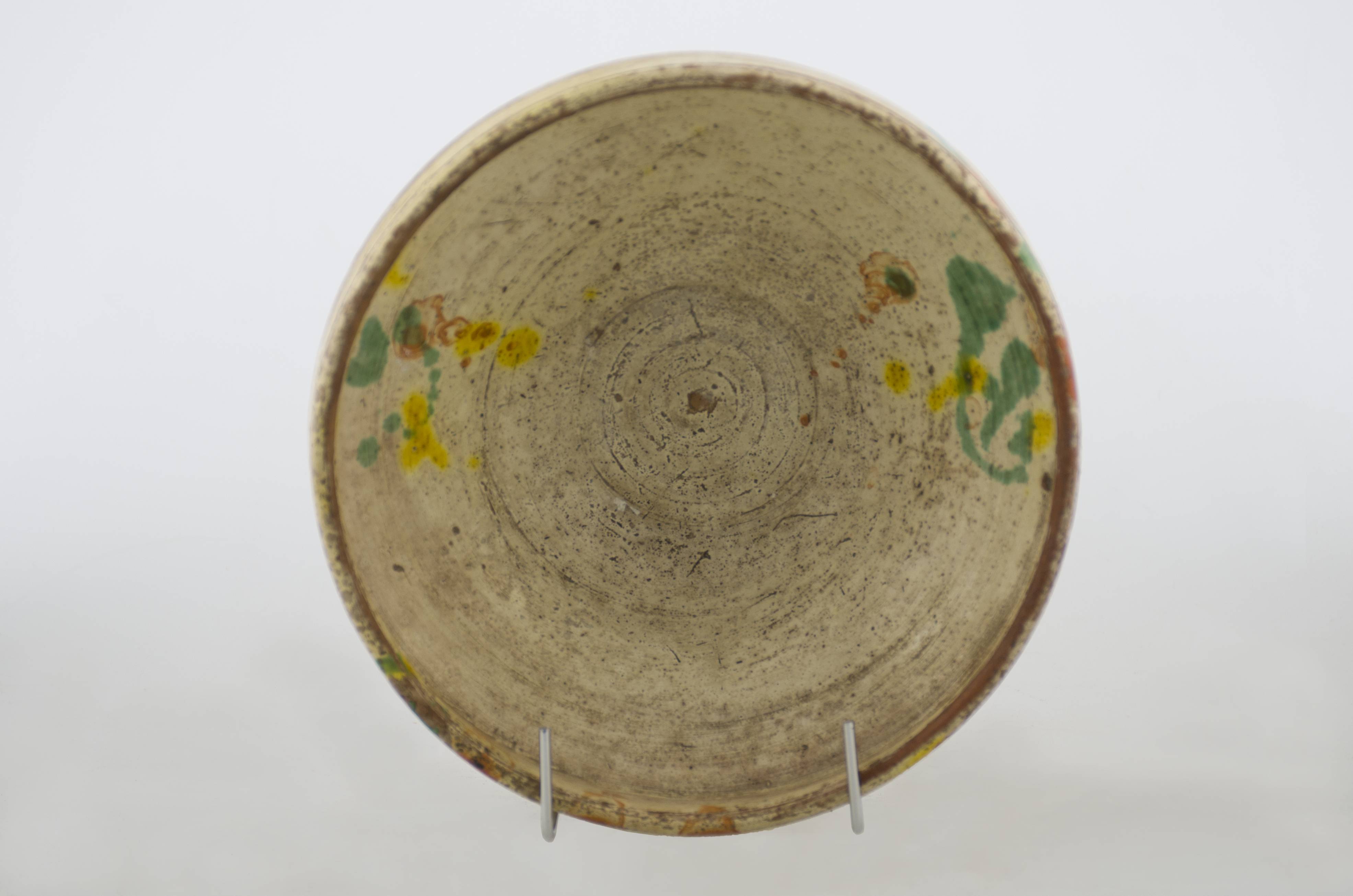 Vas ceramic de formă tronconică cu baza plată, pereții evazați și buza înaltă și ieșită înafară. Vasul este smălțuit în interior și în exterior (doar buza). Decorul este dispus pe pereții evazați ai vasului și pe exteriorul gurii fiind stropite pete de culoare verde, galben și cărămiziu. Baza exterioară a recipientului ceramic are incizate inițialele meșterului „ I. B.”. Întreaga suprafață a vasului prezintă urme de uzură, fiind cauzate de folosirea excesivă. Cromatică: fond: alb în interior; cărămiziu în exterior; motive: verde; galben; maro.