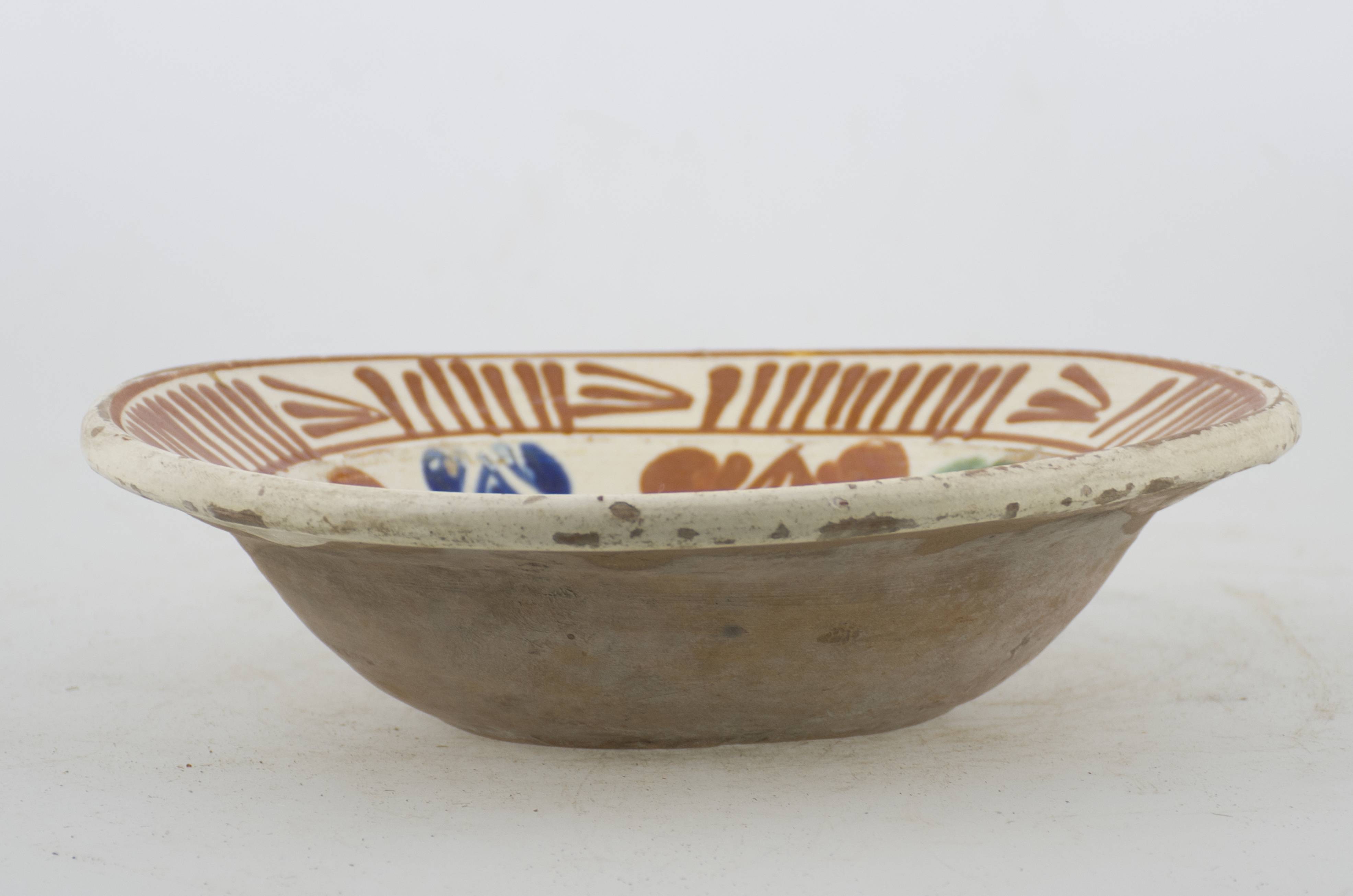 Vas ceramic de formă tronconică cu baza plată, pereții larg evazați și buza profilată. După modelarea la roată, uscarea și arderea recipientului, a fost aplicat un strat de angobă în interiorul vasului, peste care a fost pictat decorul floral și vegetal stilizat, format din două registre. Primul registru, situat pe fundul și pereții vasului, și încadrat de o linie circulară, a fost decorat cu motive geometrice și florale stilizate: două cercuri concentrice cu un punct în mijloc, au fost încadrate de opt flori (patru cărămizii, și câte două albastre și două verzi). Din vârful celor patru flori cărămizii pornesc câte două linii formând astfel două pătrate (unul interiorul celuilalt). Al doilea registru, cel care decorează buza recipientului ceramic și este mărginit, la rândul lui de o linie circulară, prezintă un brâu compus din șapte flori, despărțite de grupuri de linii verticale paralele succesive. Cromatică: crem la interior; cărămiziu la exterior; motive: albastru; verde; maro-roșcat. Prezintă uzură funcțională.