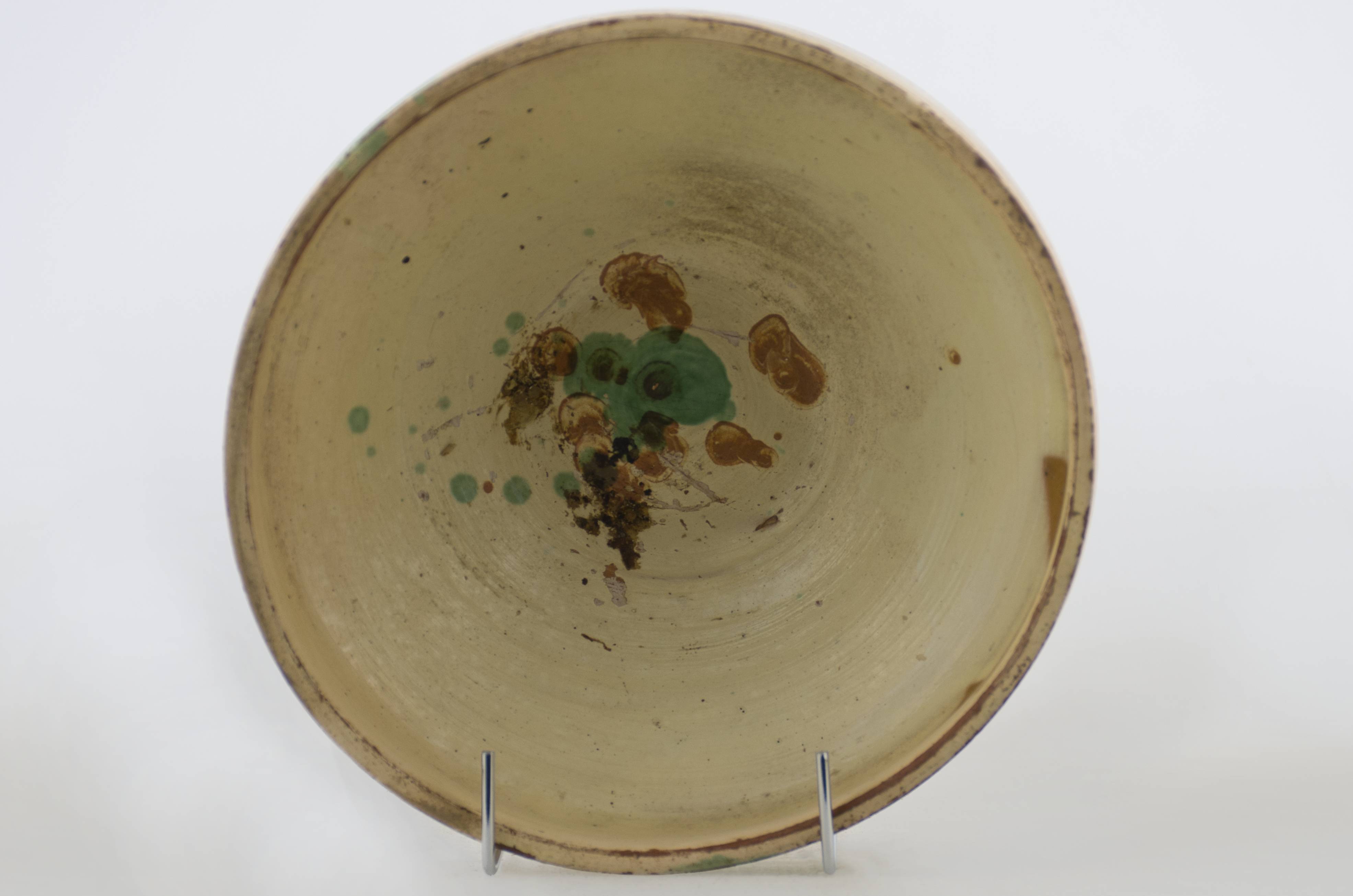 Vas ceramic de formă tronconică cu dimensiuni reduse. Prezintă baza plată, pereții oblici, buza înălțată și ieșită înafară. Vasul este decorat cu motive vegetale stilizate realizate din stropi amplasate în centru. Baza exterioară a recipientului ceramic are incizate inițialele meșterului „I. B.”. Cromatică: fond: alb; motive: verde; maro.