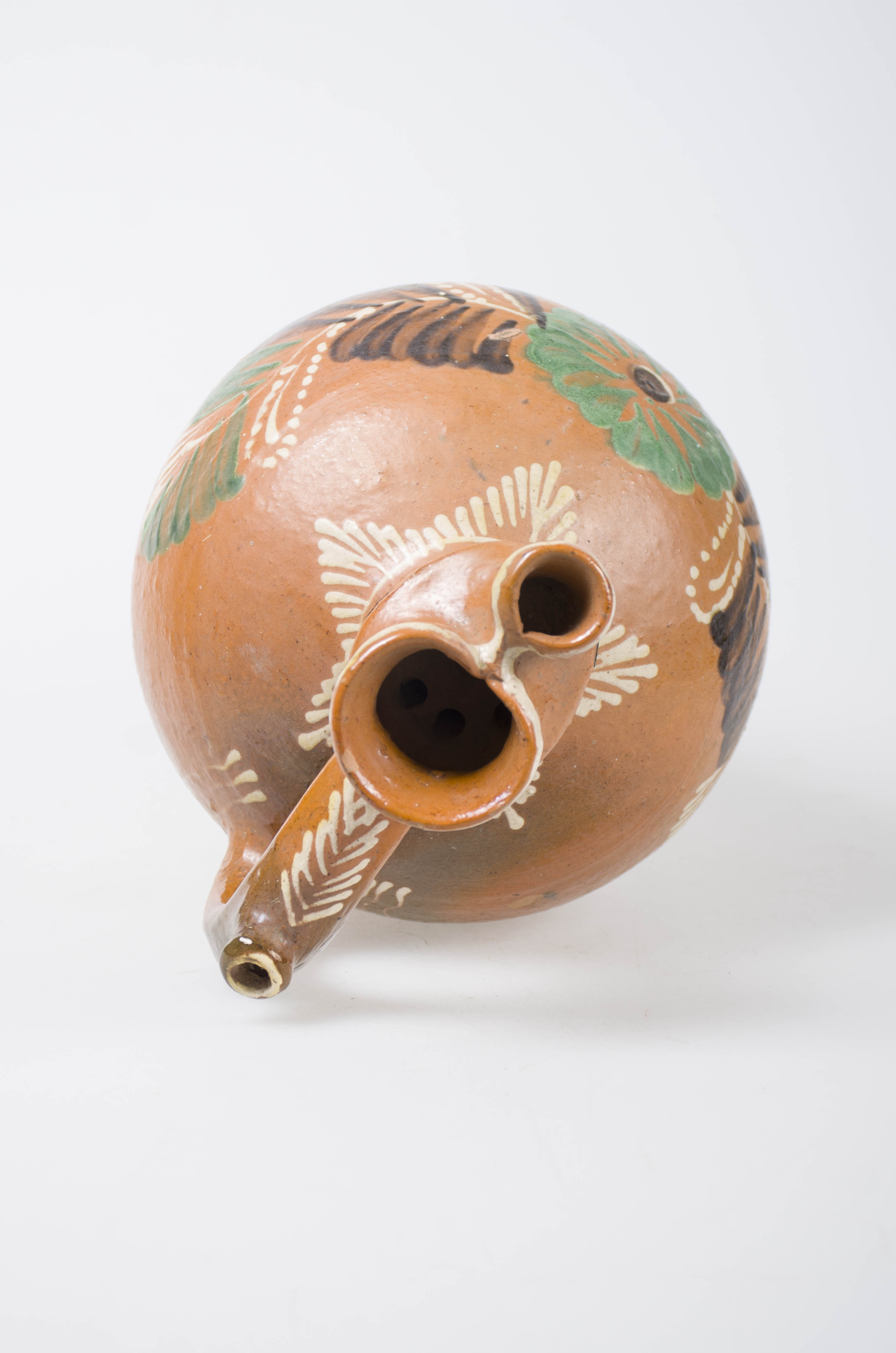 Obiect ceramic de formă bitronconică cu gâtul scurt și gura bilobată. Toarta este prevăzută cu ”țâță”. Decorul este amplasat pe toată suprafața și este format din motive florale și geometrice (linii, cercuri, meandre). Cromatică: fond: maro; motive: verde; maro închis; alb.