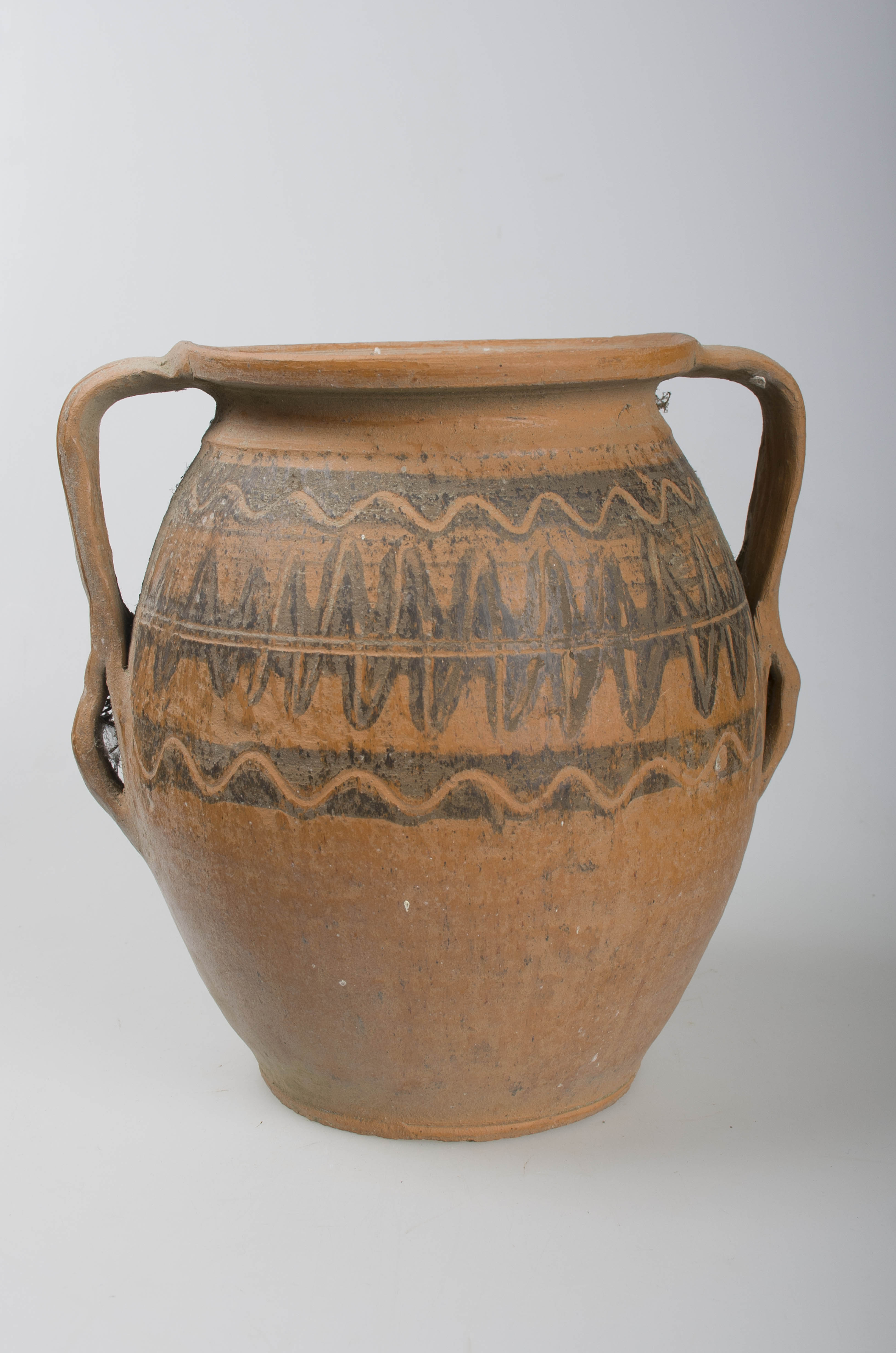 Vas ceramic de formă sferoidală, bombat în partea mediană, cu gât scurt și larg, buză rotunjită. Vasul prezintă două toarte ce leagă gura cu partea de diametru maxim a vasului, continuate după prinderea pe pântec cu câte două urechi de mici dimensiuni. Prezintă ornamentații în partea superioară ilustrând motivul dintelui de lup, specific centrului ceramic Săcel, dispus în alternanță pe ambele părți a unei linii continue incizate dispuse circular, încadrată de două dungi negre, peste cea din partea superioară se suprapune o linie vălurită incizată iar pe cea din partea inferioară se suprapune o linie ondulată incizată. Peste registrul decorativ principal se suprapun ușoare incizii ce urmează linia decorației centrale. Cromatică: cărămiziu; negru.
