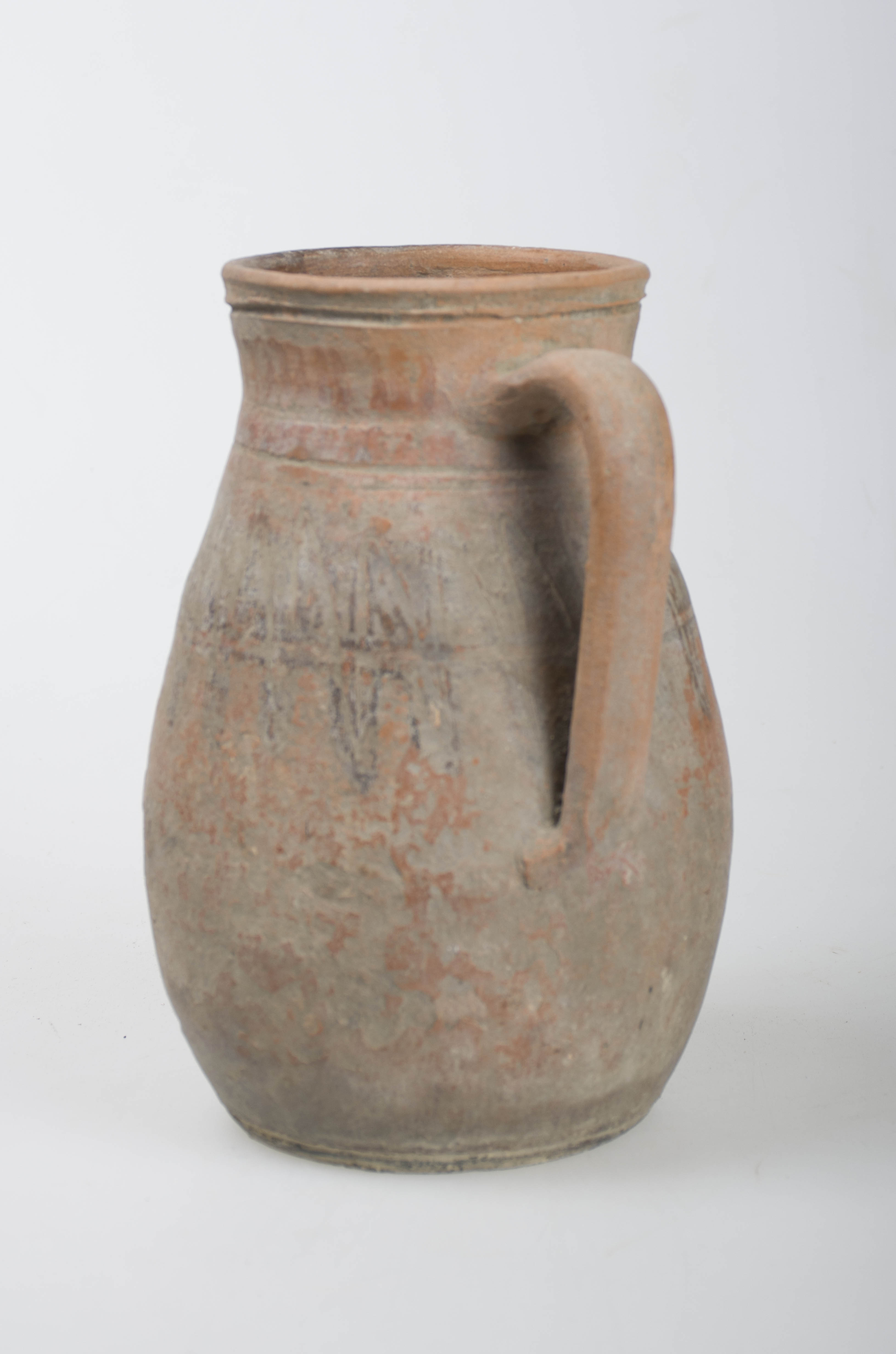 Vas ceramic de formă aproximativ cilindrică, realizat manual pe roată. Vasul prezintă bază lată din care se ridică pereții ușor evazați, zona mediană ușor bombată, îngustându-se în zona gâtului, deschizându-se cu gura largă ușor evazată. Pe o parte are o toartă laterală ce porneste din mijlocul gâtului și se termină în partea cea mai bombată. Imediat sub gât și trecând pe sub toartă prezintă o zonă de decor pictat cu motive geometrice, linie în zig-zag. La baza gurii și la gât prezintă amplasată câte o linie incizată orizontală și circulară. Cromatică: cărămiziu; negru.