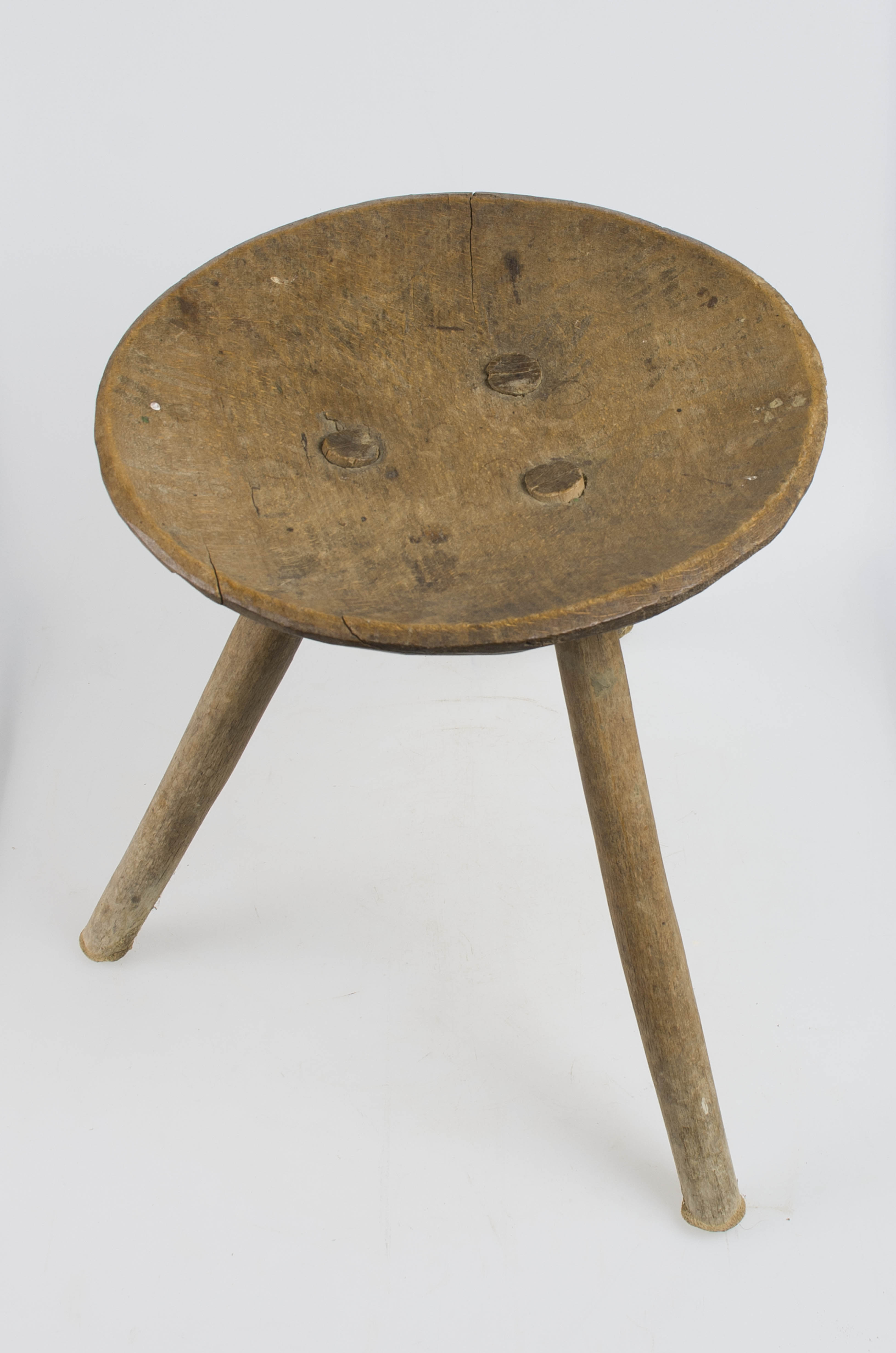 Piesă de mobilier din lemn, de mici dimensiuni, prevăzută cu blat circular. În centrul blatului sunt realizate prin găurire trei orificii, în care sunt fixate cele trei picioare circulare în secțiune, dispuse oblic. Prezintă uzură funcțională. Cromatică: culoarea patinată a lemnului.