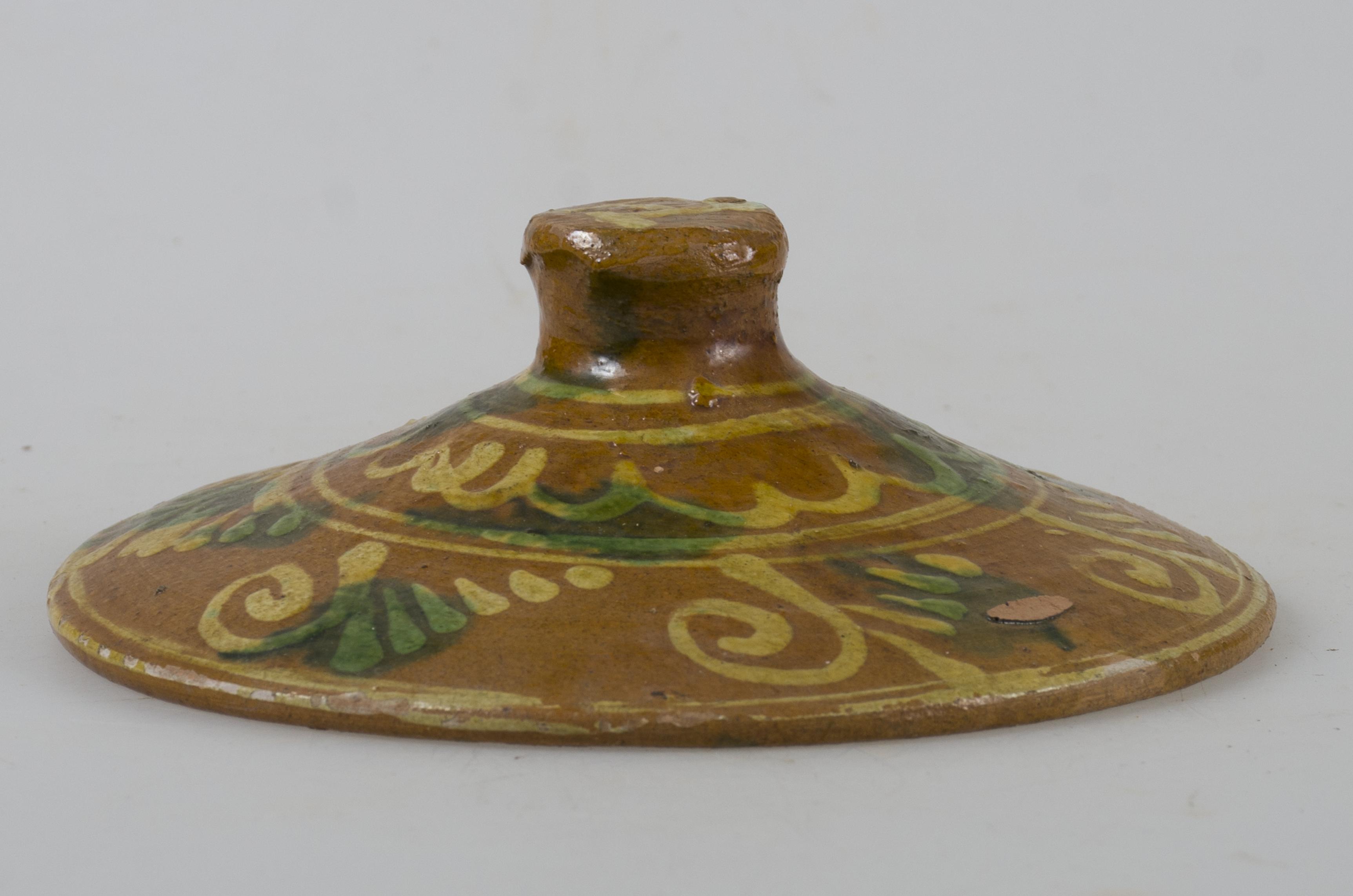 Obiect de formă tronconică. Decorul amplasat pe toată suprafața superioară și este reprezentat de motive geometrice (spirală, cerc, meandru). Cromatică: fond: maro; motive: verde, alb, galben.