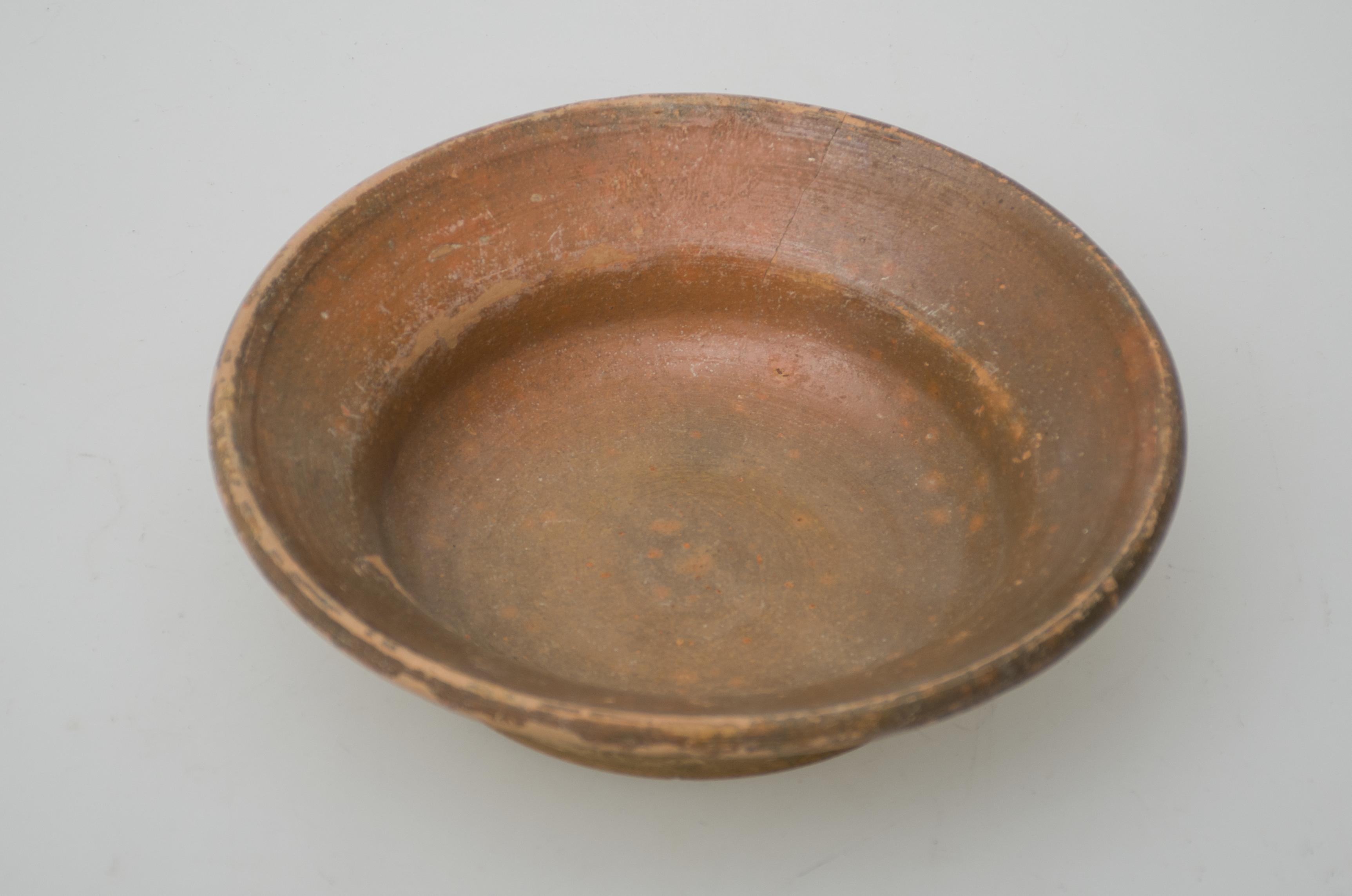 Farfurie din ceramică, joasă, de formă tronconică, cu buza mult evazată și fundul inelar. Vasul este smălțuit doar la interior. Pe fund sunt pictate cu pensula, două linii albe ce se intersectează. Cromatică: fond: cărămiziu interior-exterior; motive: alb exterior.