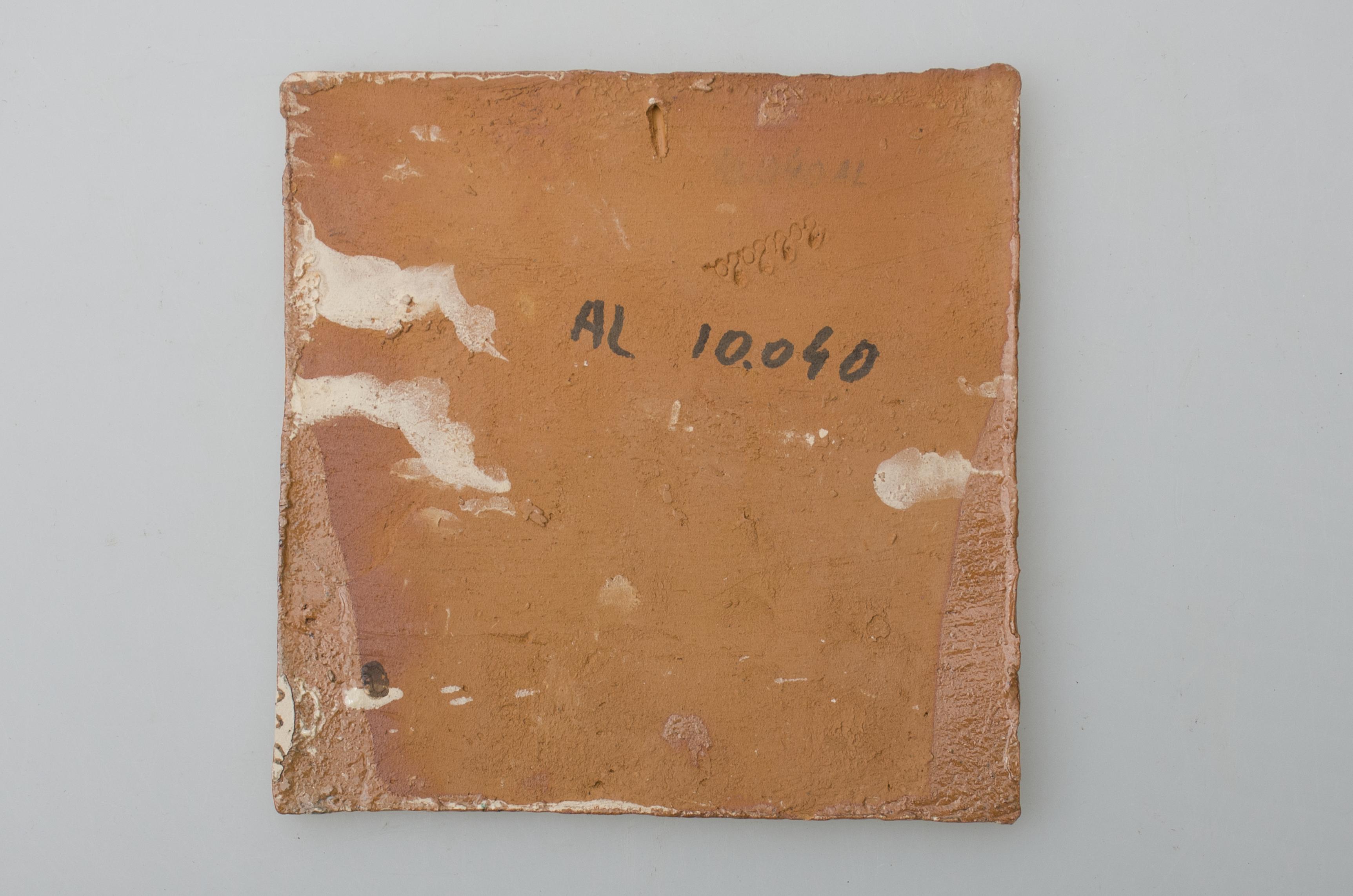 Piesă ceramică de formă pătrată, smălțuită și angobată, cu rol decorativ. Laturile pătratului sunt marcate de două chenare, primul vălurit, al doilea în linie dreaptă. Este ilustrat motivul petrecerii: doi oameni cu pălărie pe cap stau față în față. Unul cântă la vioară, iar celălalt închină un pahar cu mâna dreaptă. Între ei, este pictată o măsuță cu o carafă și un pahar. În partea superioară a plăcii este pictată o mică fereastră, iar în partea inferioară, trei flori. Motivele au fost la început incizate, iar apoi pictate. Pe spate, cahla este prevăzută cu un orificiu pentru prinderea aței. Tot aici, este inscripționat numele meșterului olar, "Colibaba". Cromatică: fond: alb; motive: verde, galben, maro, negru.