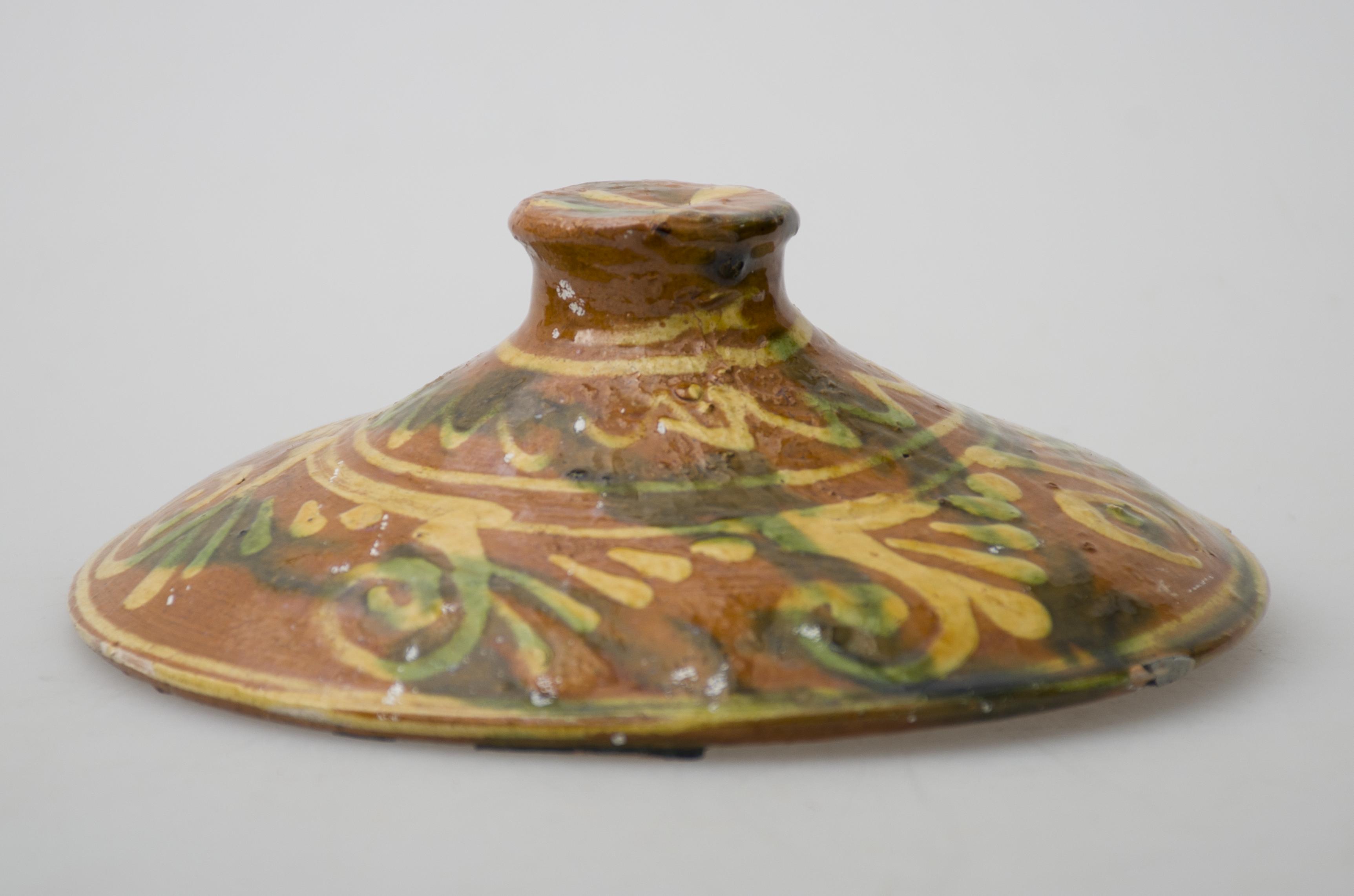 Obiect ceramic de uz casnic, de formă tronconică, smălțuit. Prevăzut cu pereți oblici, care se termină în partea superioară cu un bumb de formă circulară, pentru manipulare. Este decorat la exterior cu motive geometrice, amplasate pe toată suprafața: linii circulare, linii vălurite, spirale; linii drepte dispuse orizontal. Cromatică: fond cărămiziu; motive: galben, verde.
